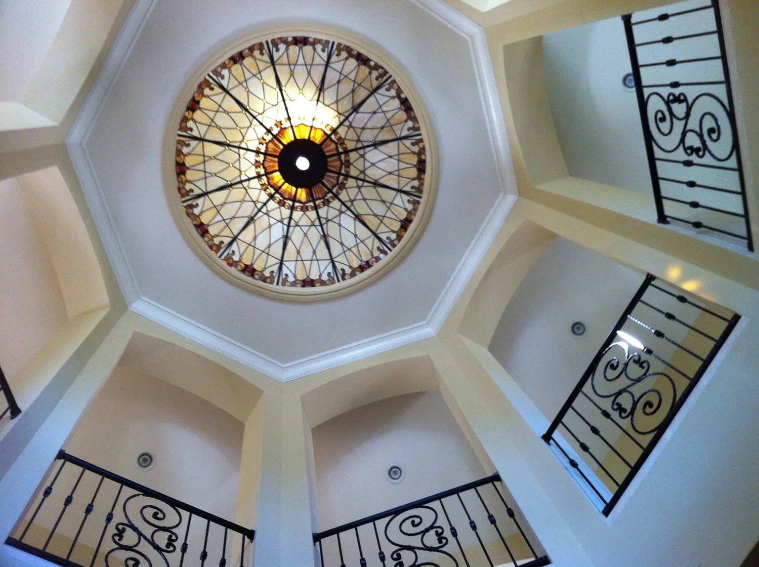 View of a glass stained ceiling with decorative iron railings on upper balconies.