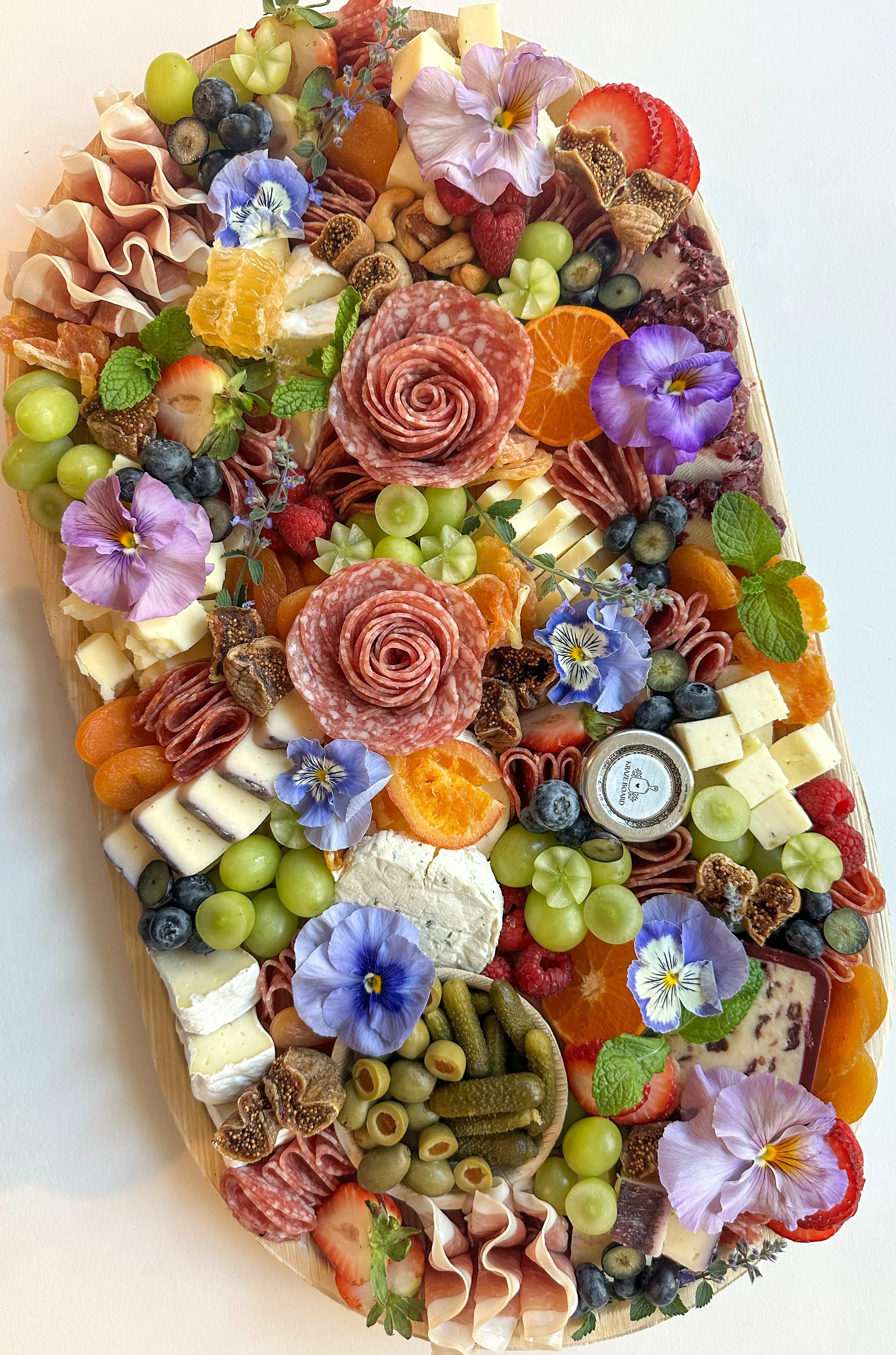 Cheese and fruit platter with flowers and a 'happy birthday' sign.