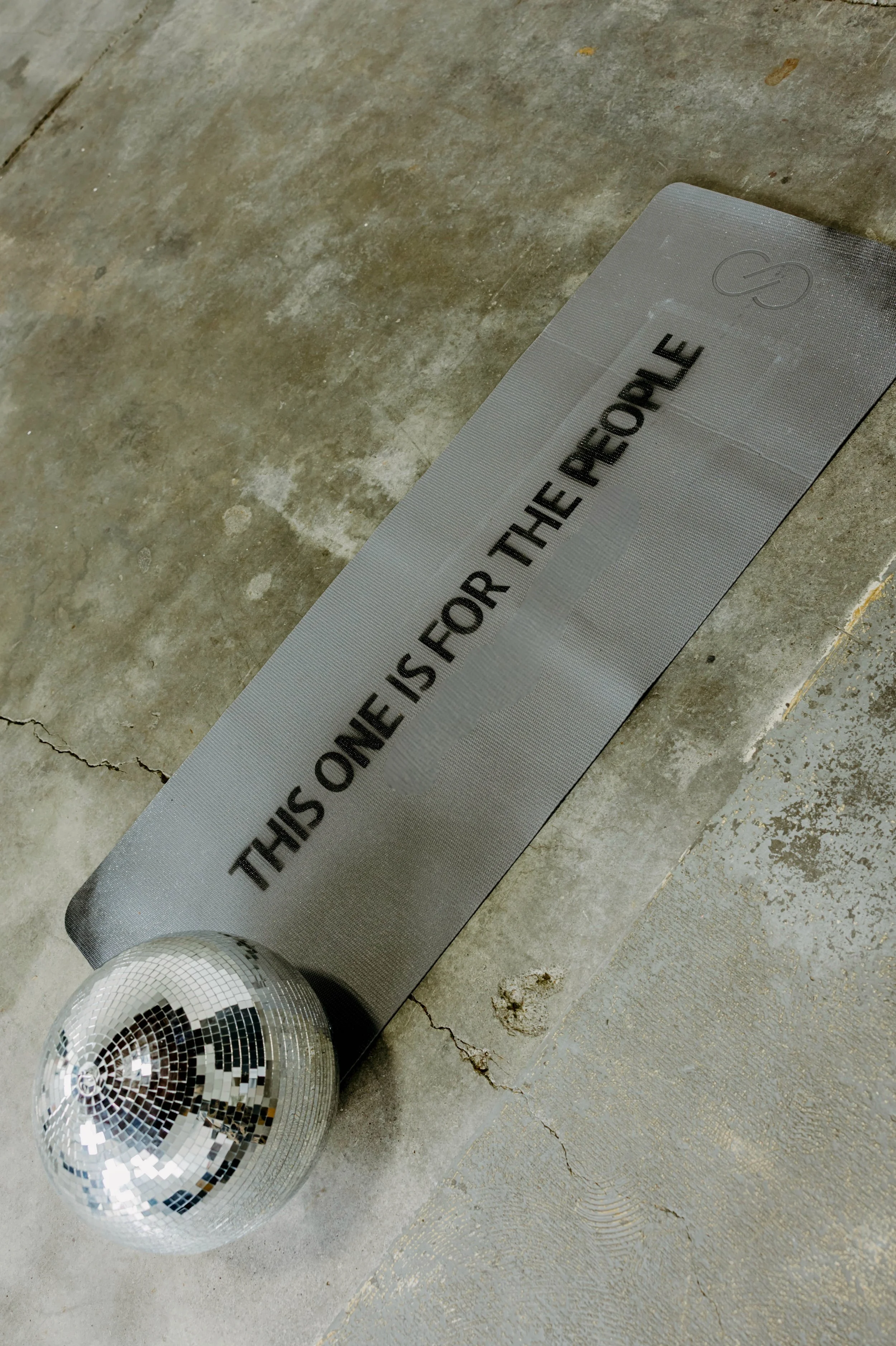 Yoga Mat spray painted with This One is For The People on the floor with a disco ball.