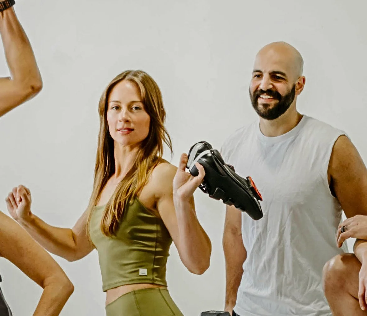 woman holding cycling shoes smiling with partner behind her.