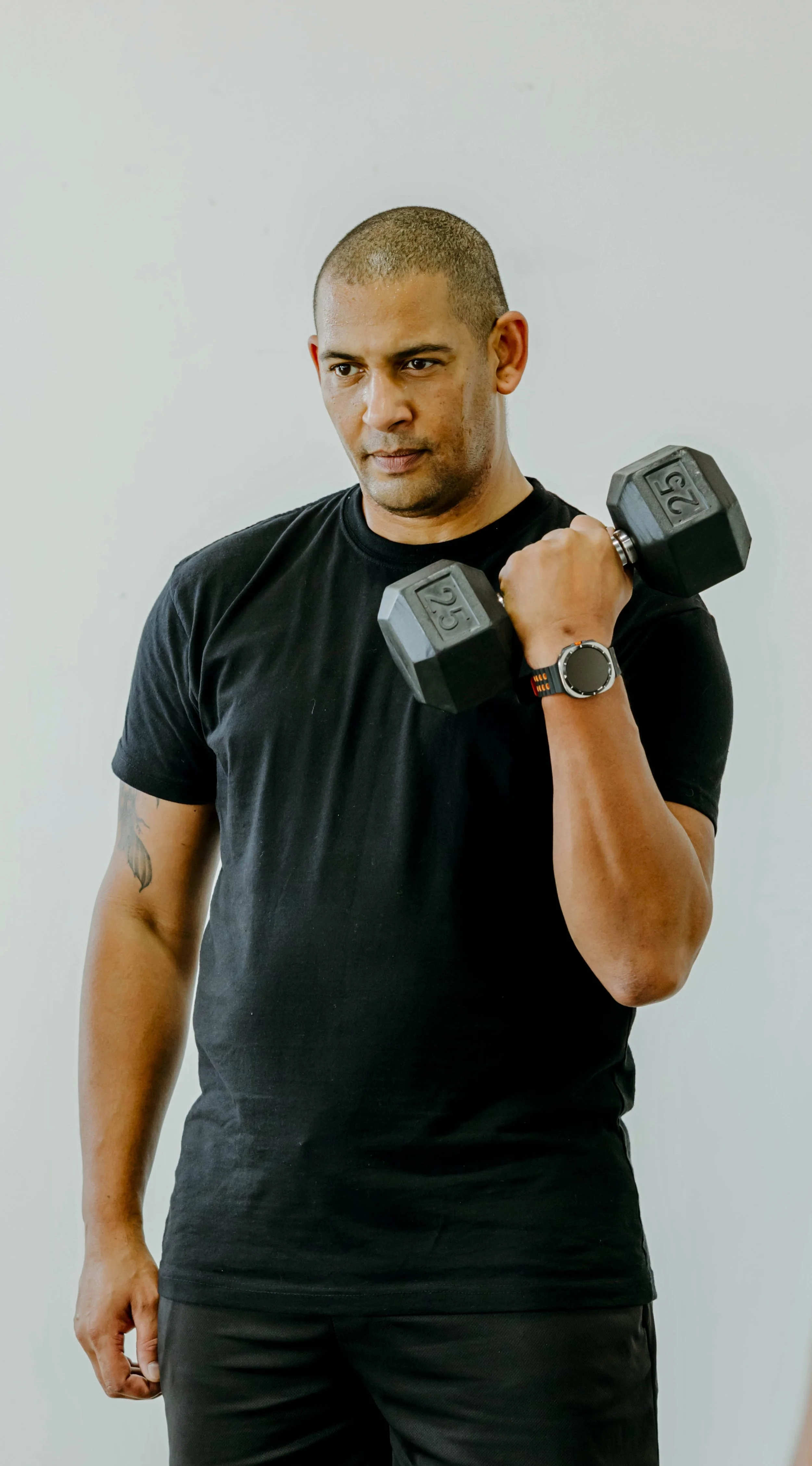 Man in black T shirt curling a weight.