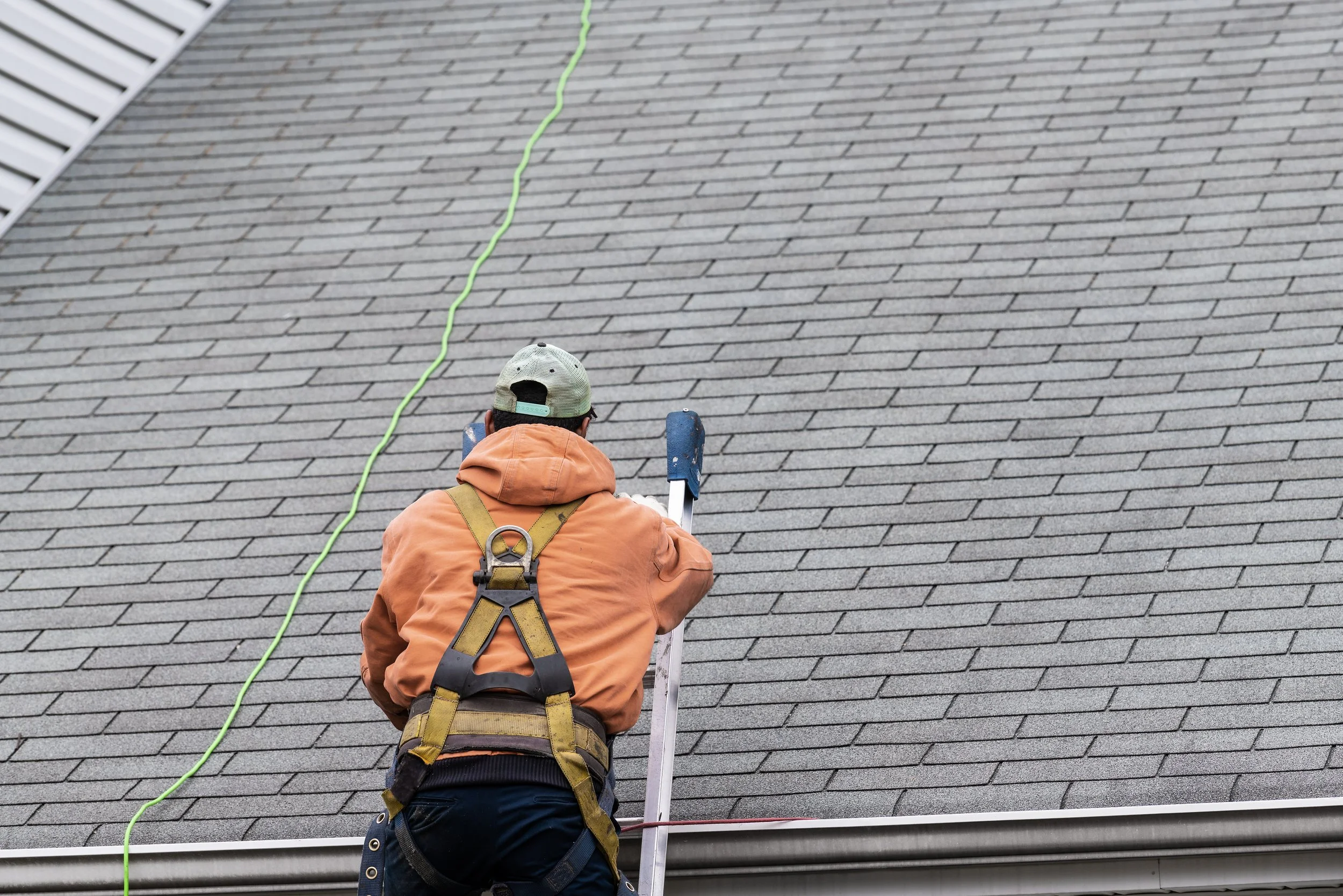 Man on a ladder climbing onto a roof