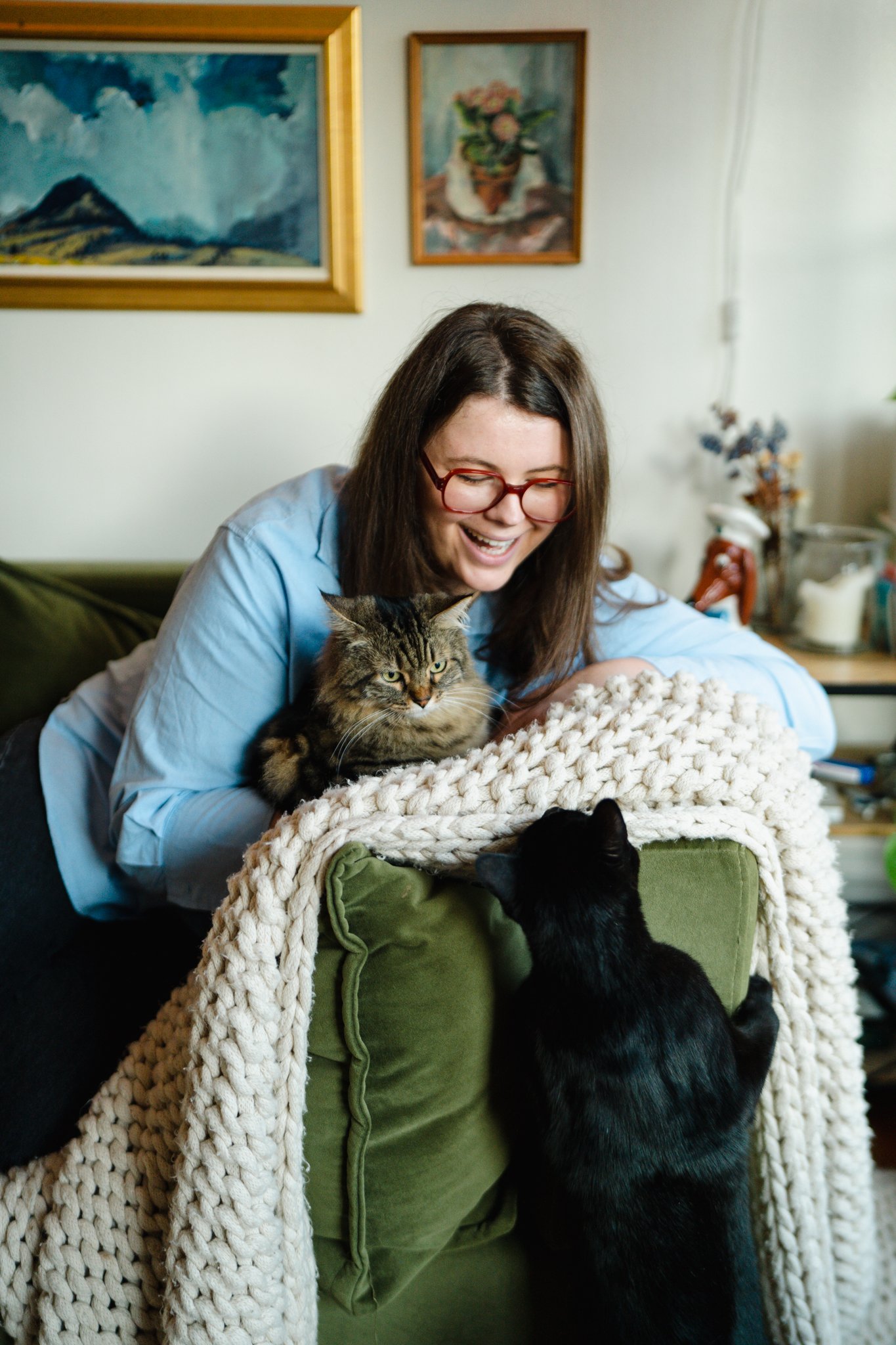 Portrait of a woman at home surrounded by art with her cats
