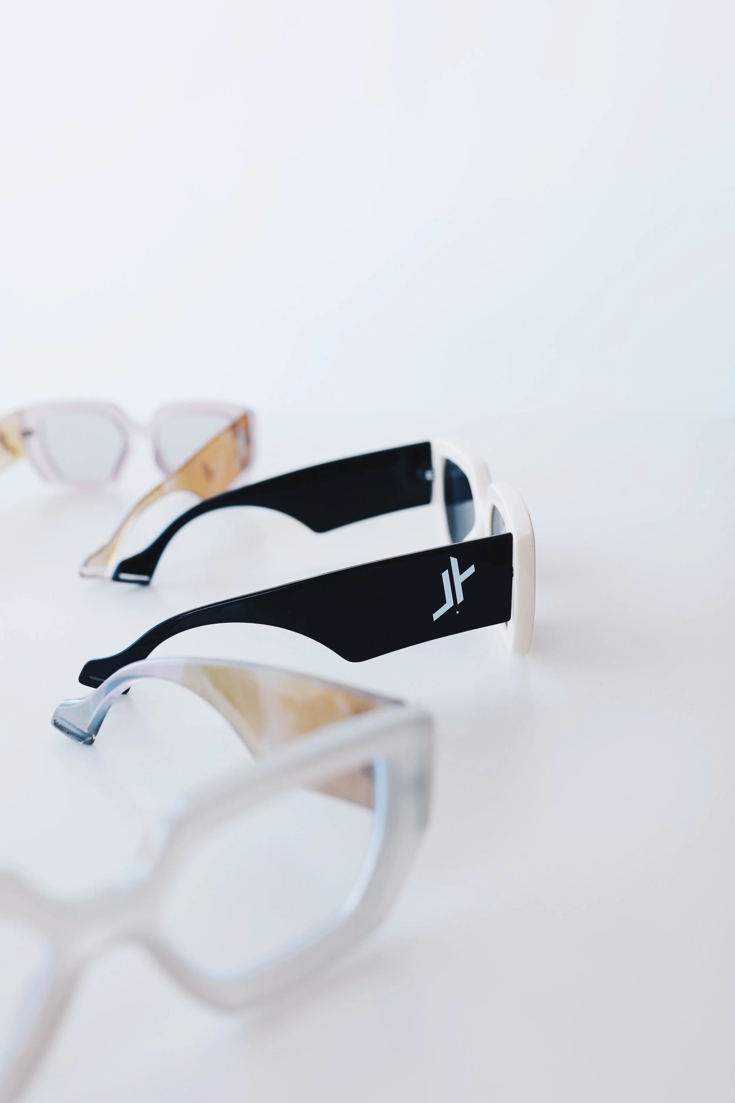 Three pairs of stylish sunglasses in different colors and styles on a white surface.