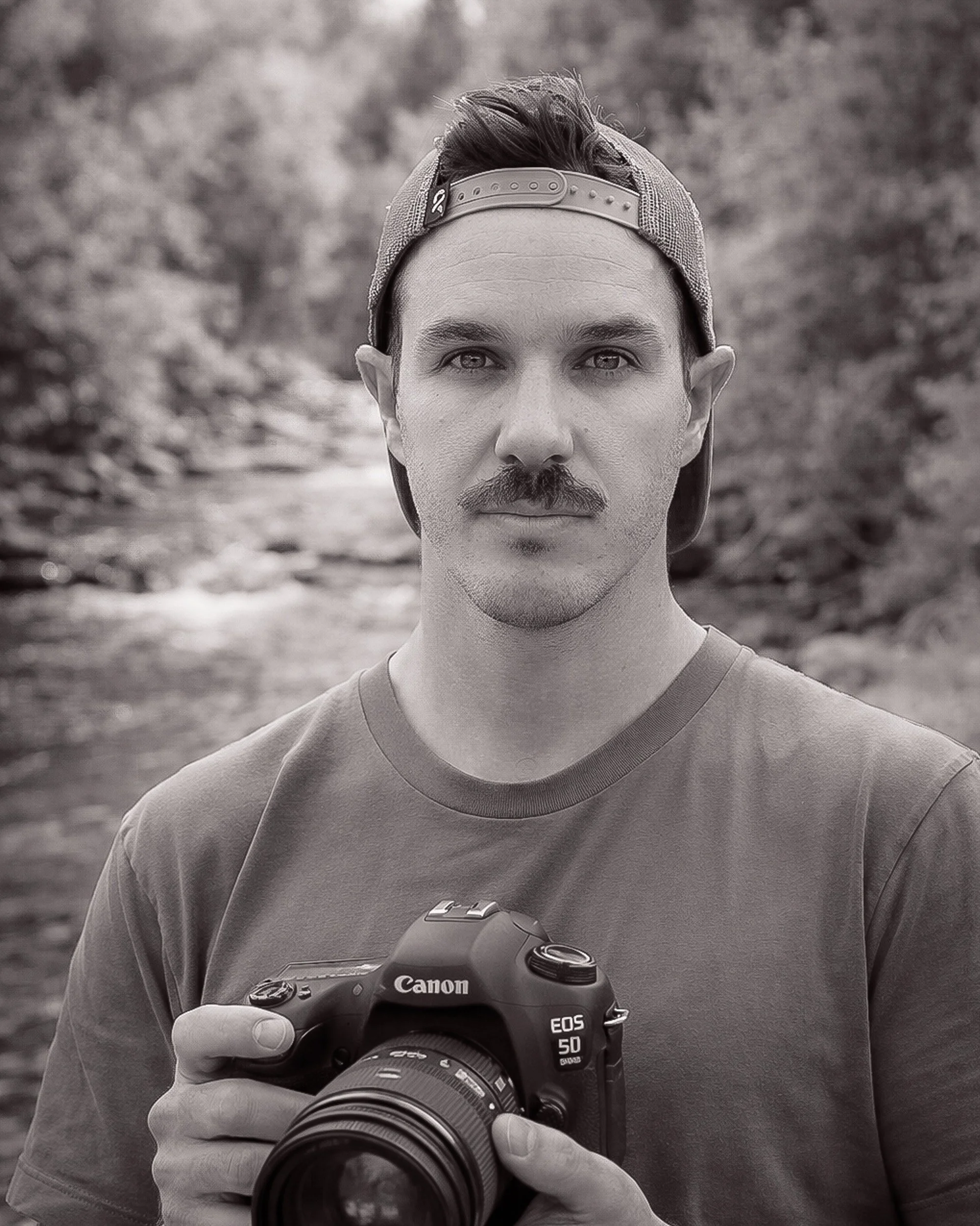 Levi Watson man with hat and camera in the woods