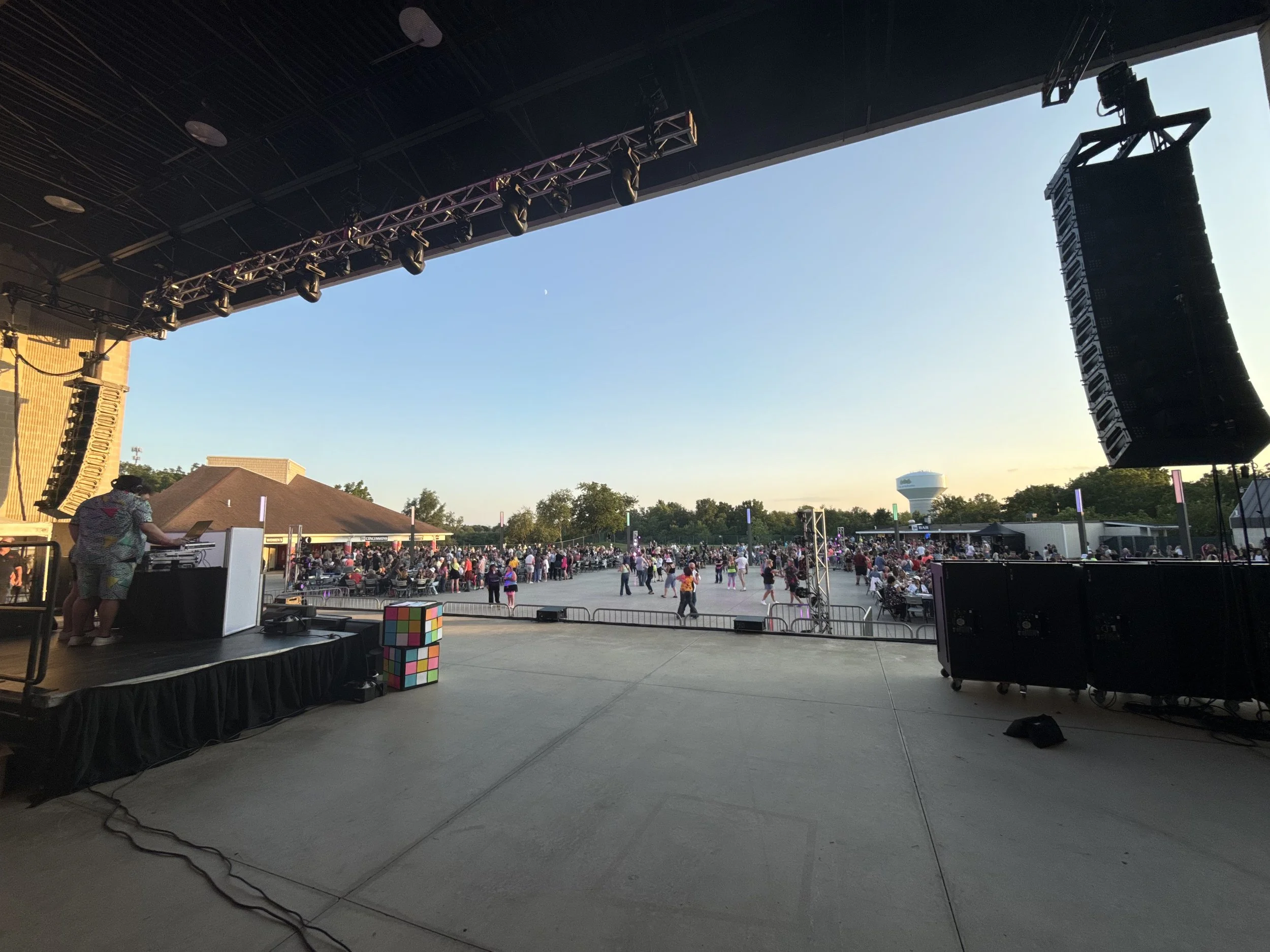 Scenic landscape with a large lake, green hills, and mountains in the background under a cloudy sky.