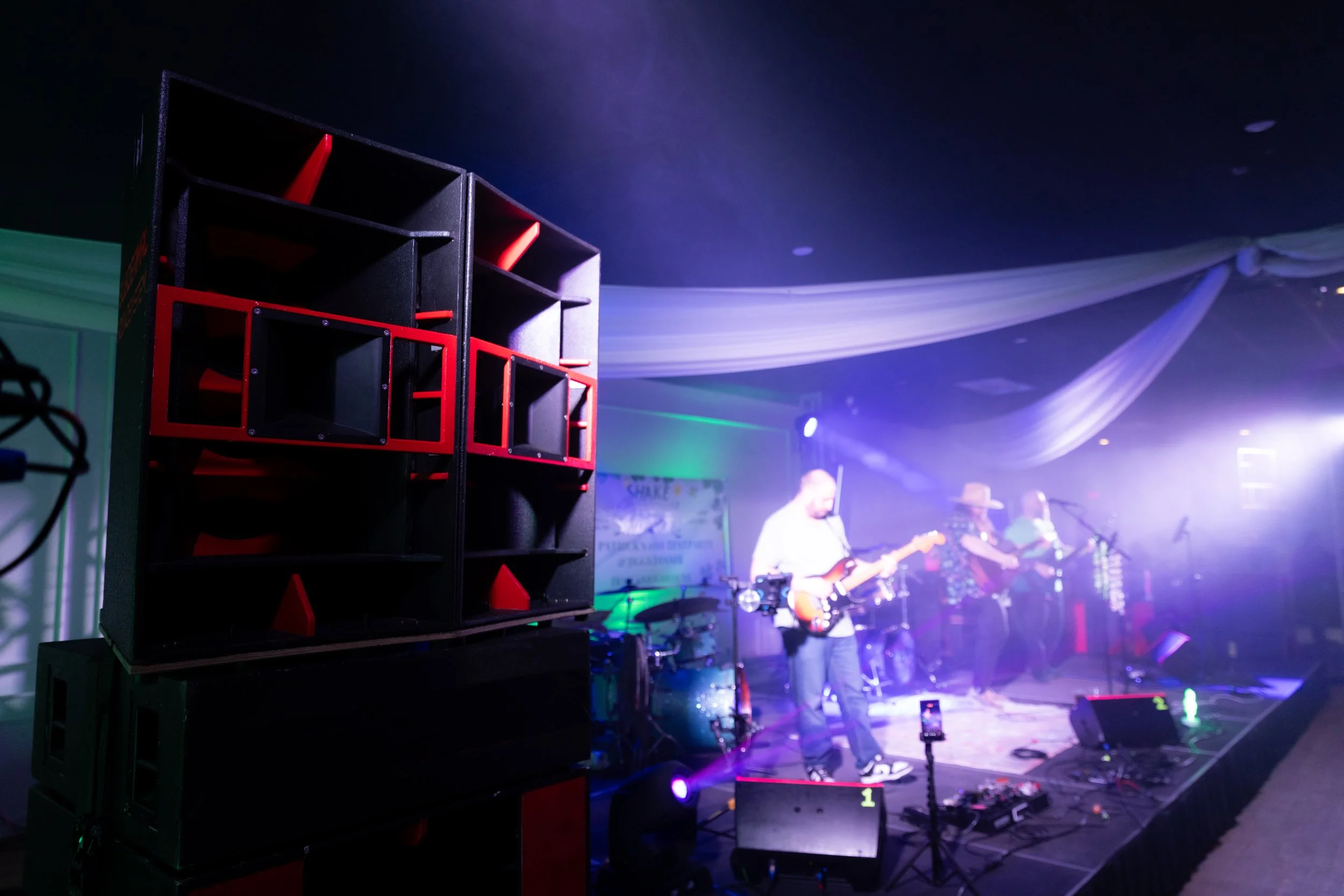 Scenic landscape with a large lake, green hills, and mountains in the background under a cloudy sky.