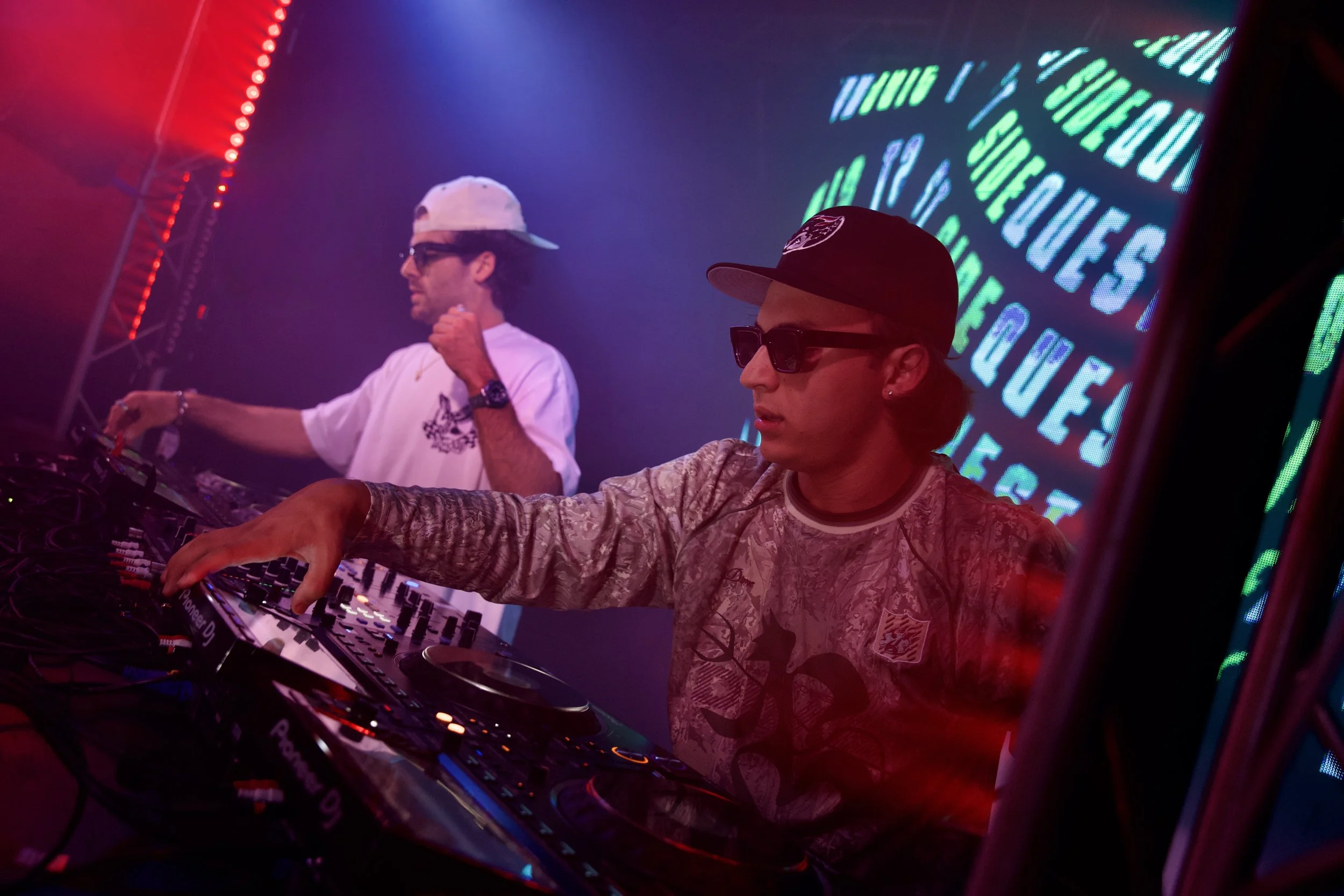 Modern house on a grassy hilltop with snow-capped mountains in the background under an overcast sky.