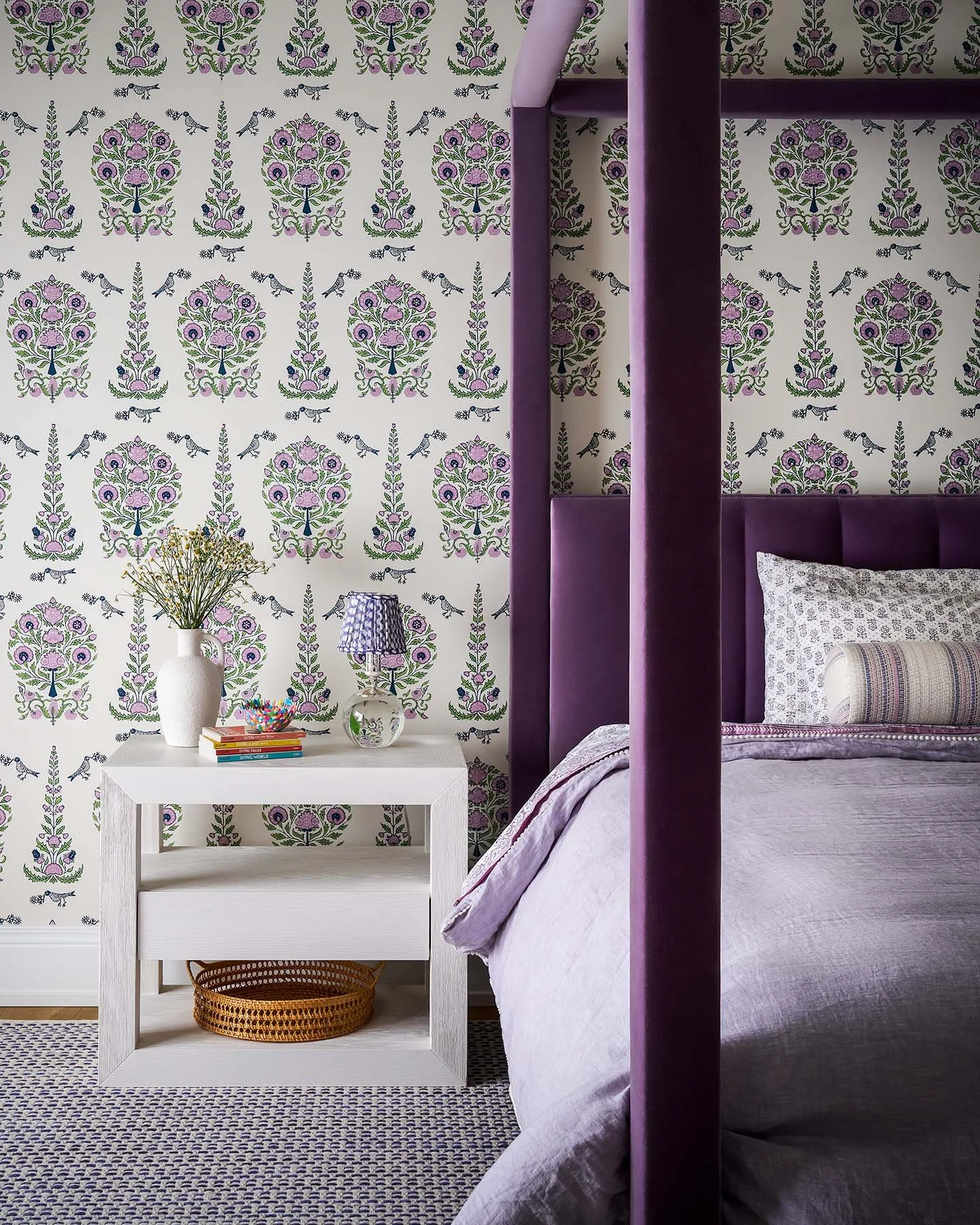 Girls bedroom detail with purple canopy bed, floral wallpaper, and white nightstand styling in Kenilworth family home.