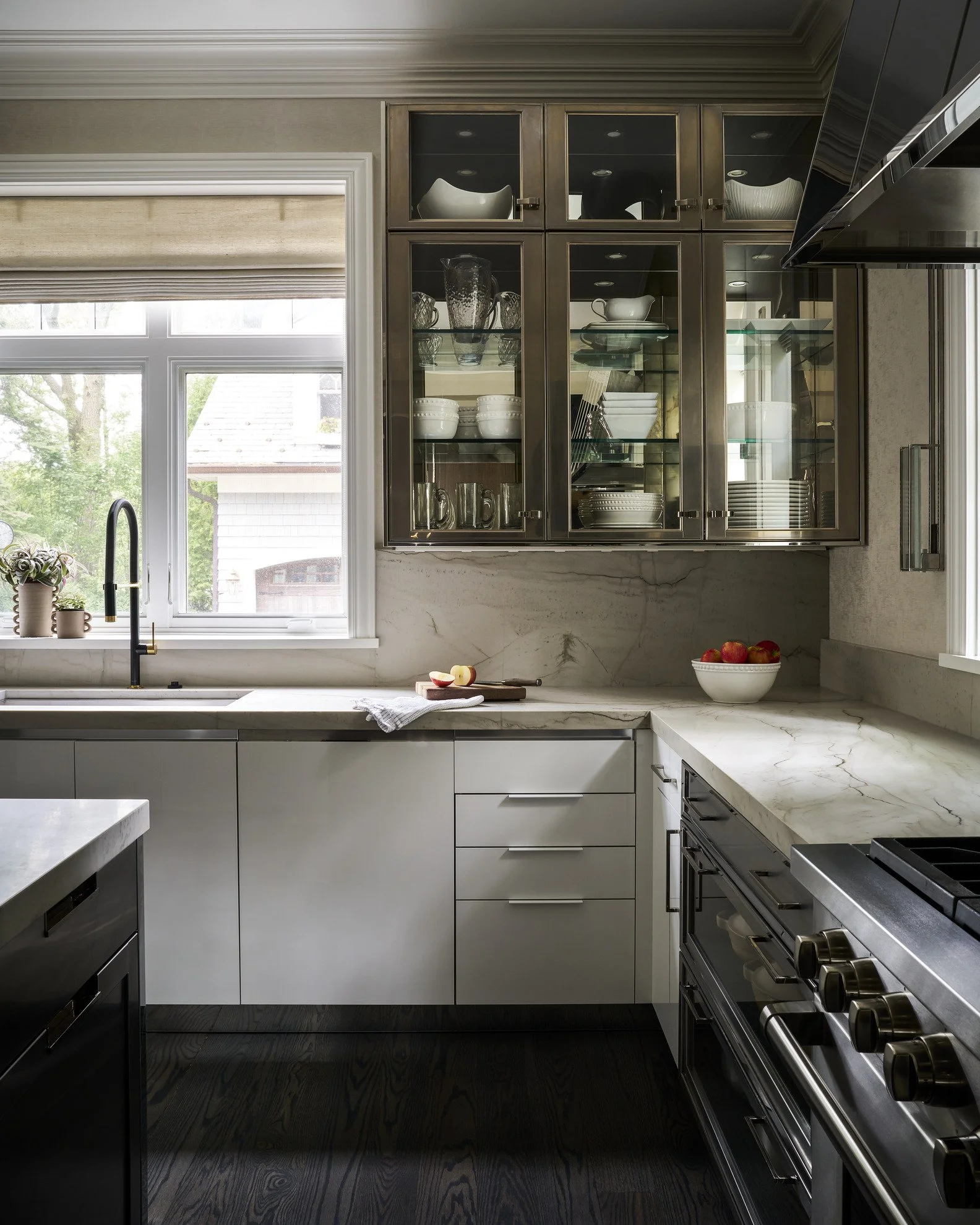 Custom kitchen with glass-front cabinetry and marble countertops designed by Jen Marie Interiors.