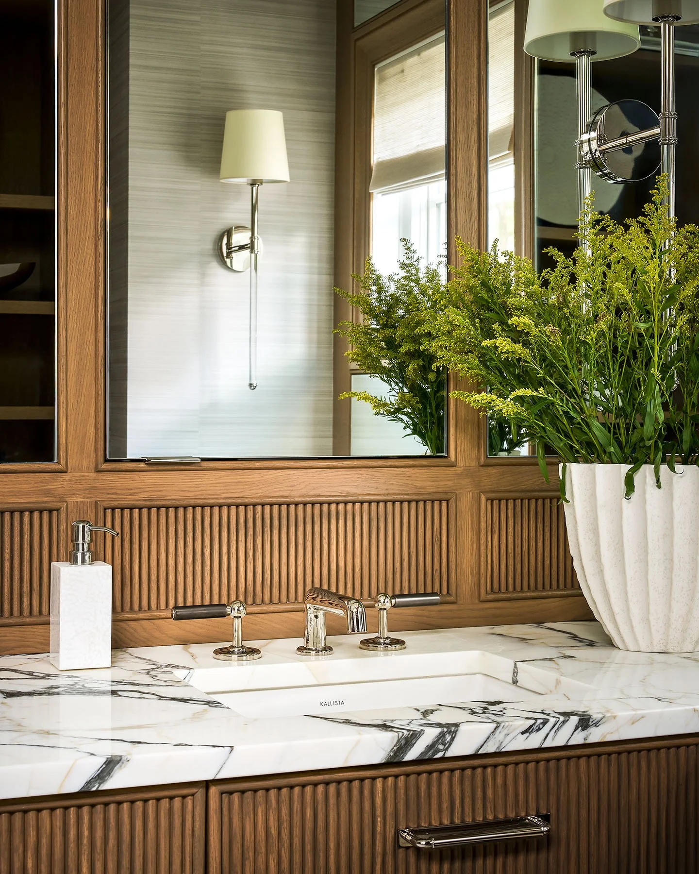 Marble bathroom countertop with polished nickel faucet and fluted wood cabinetry detail.