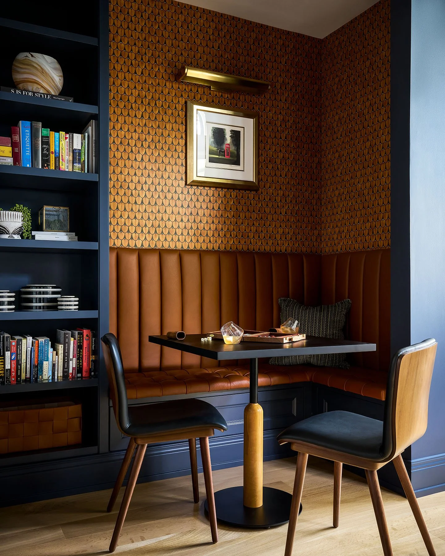 Cozy breakfast nook with leather banquette seating, custom shelving, and warm accent lighting.