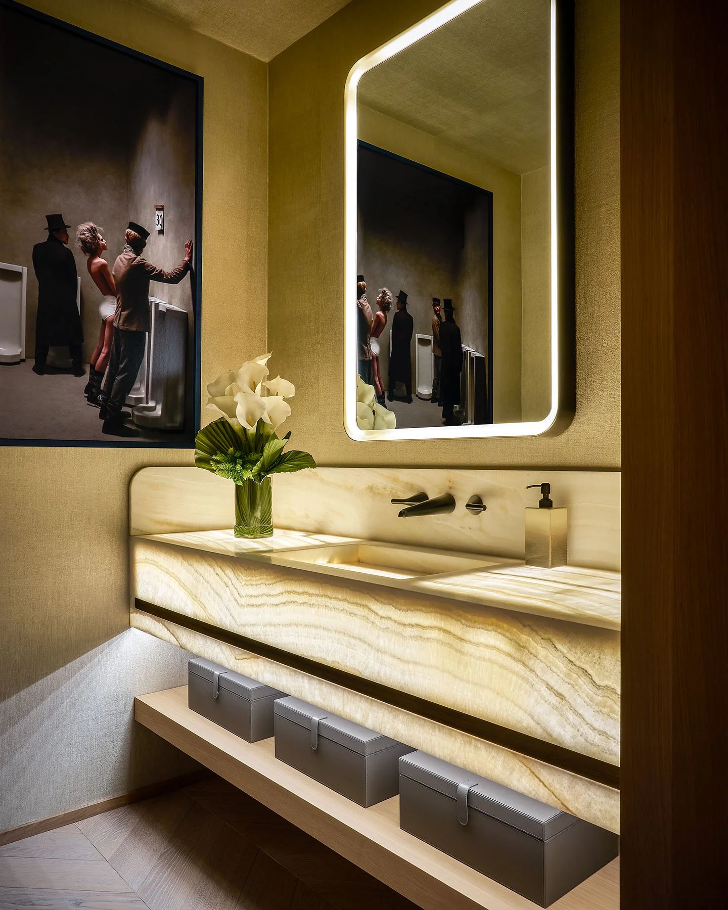 Luxury powder room with illuminated onyx vanity, floating shelf, and backlit mirror.