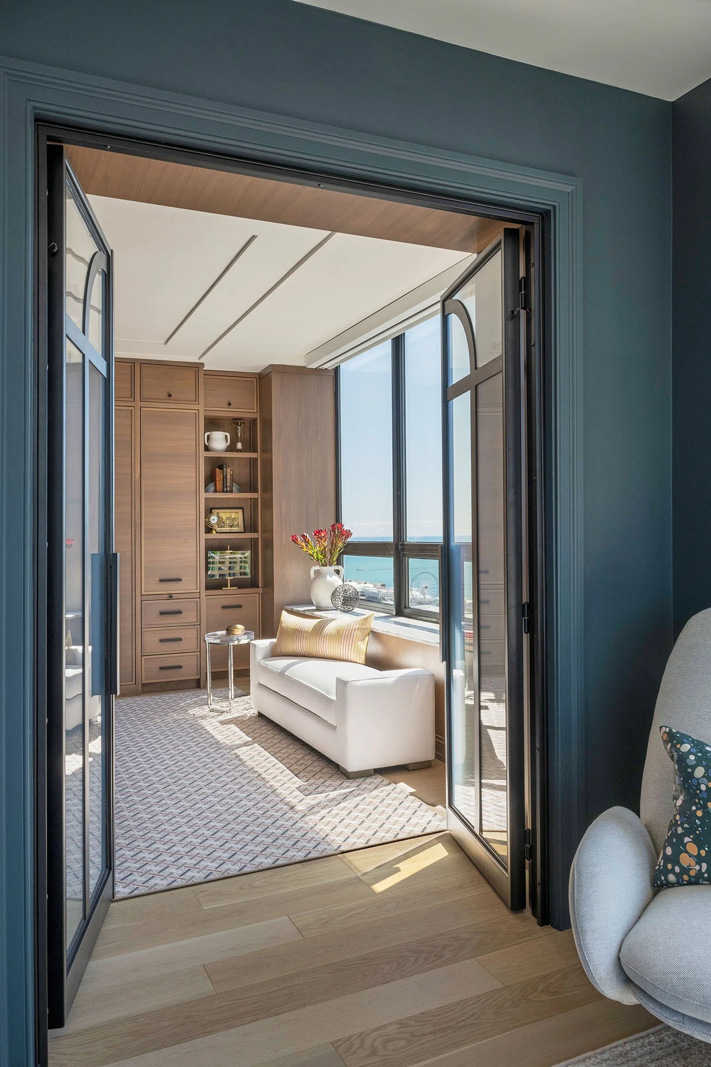 Luxury reading nook with built-in wood cabinetry, upholstered bench seating, and large windows overlooking the lake.