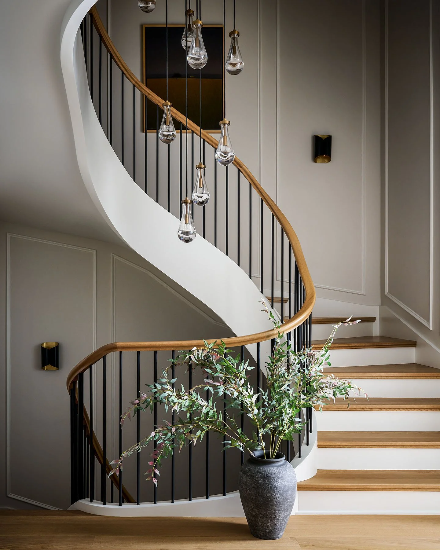 Architectural curved staircase with wood handrail and modern pendant lighting in Kenilworth custom home.