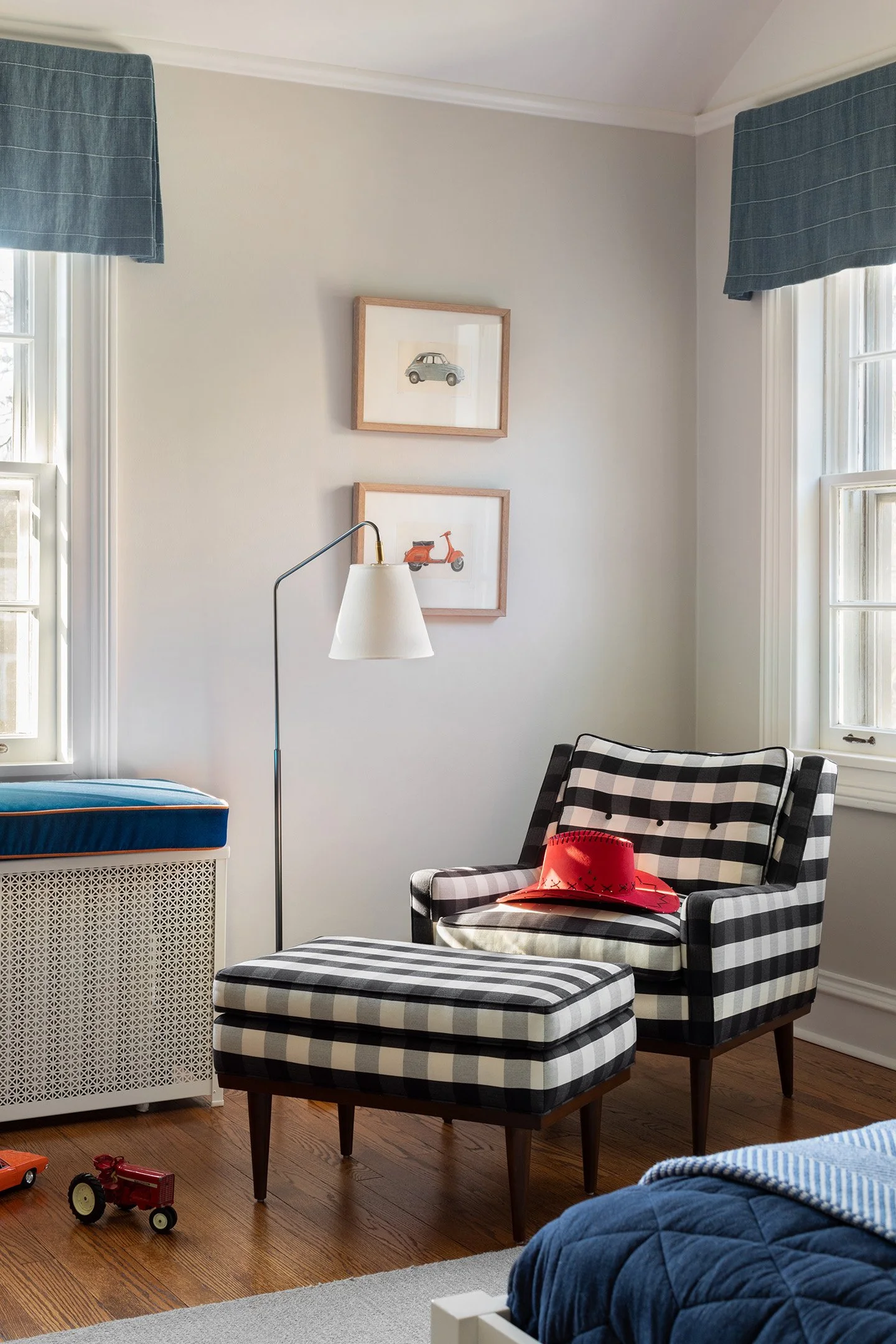 Boys bedroom with black and white gingham chair, matching ottoman, and blue window valances.