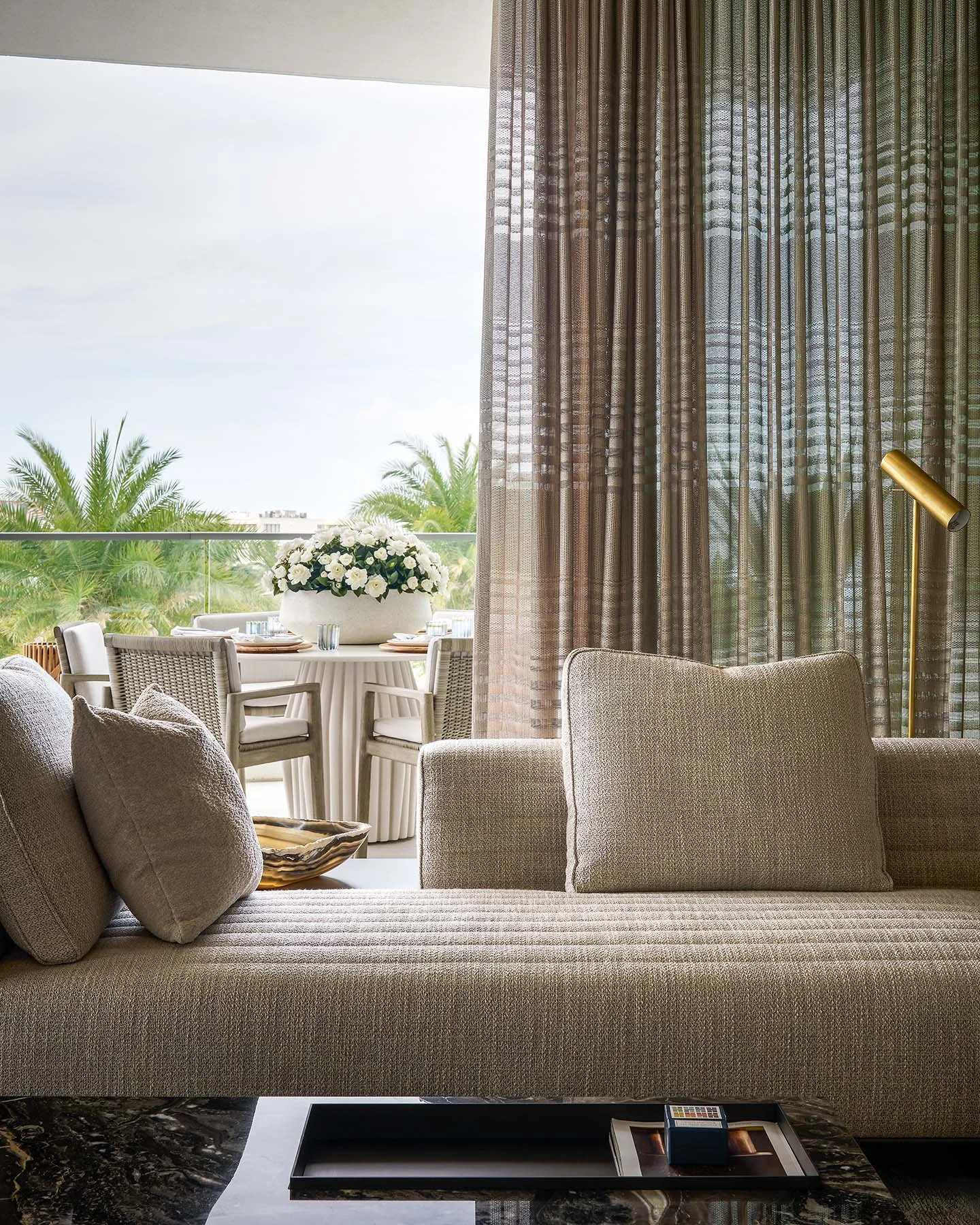 Luxury balcony dining area with outdoor kitchen, greenery wall, and modern round dining table.