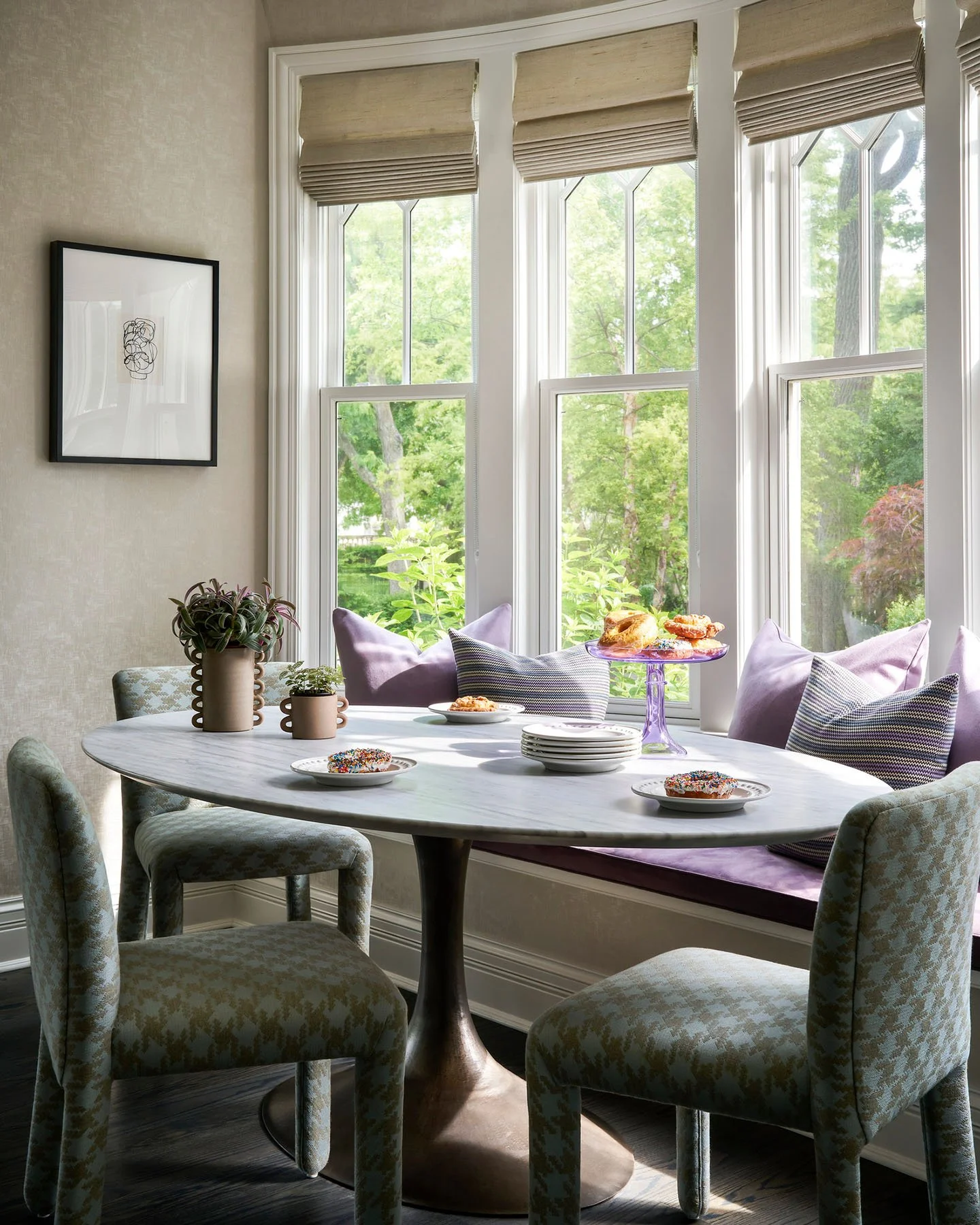 Bright breakfast nook with marble pedestal table and built-in window seating in Kenilworth residence.