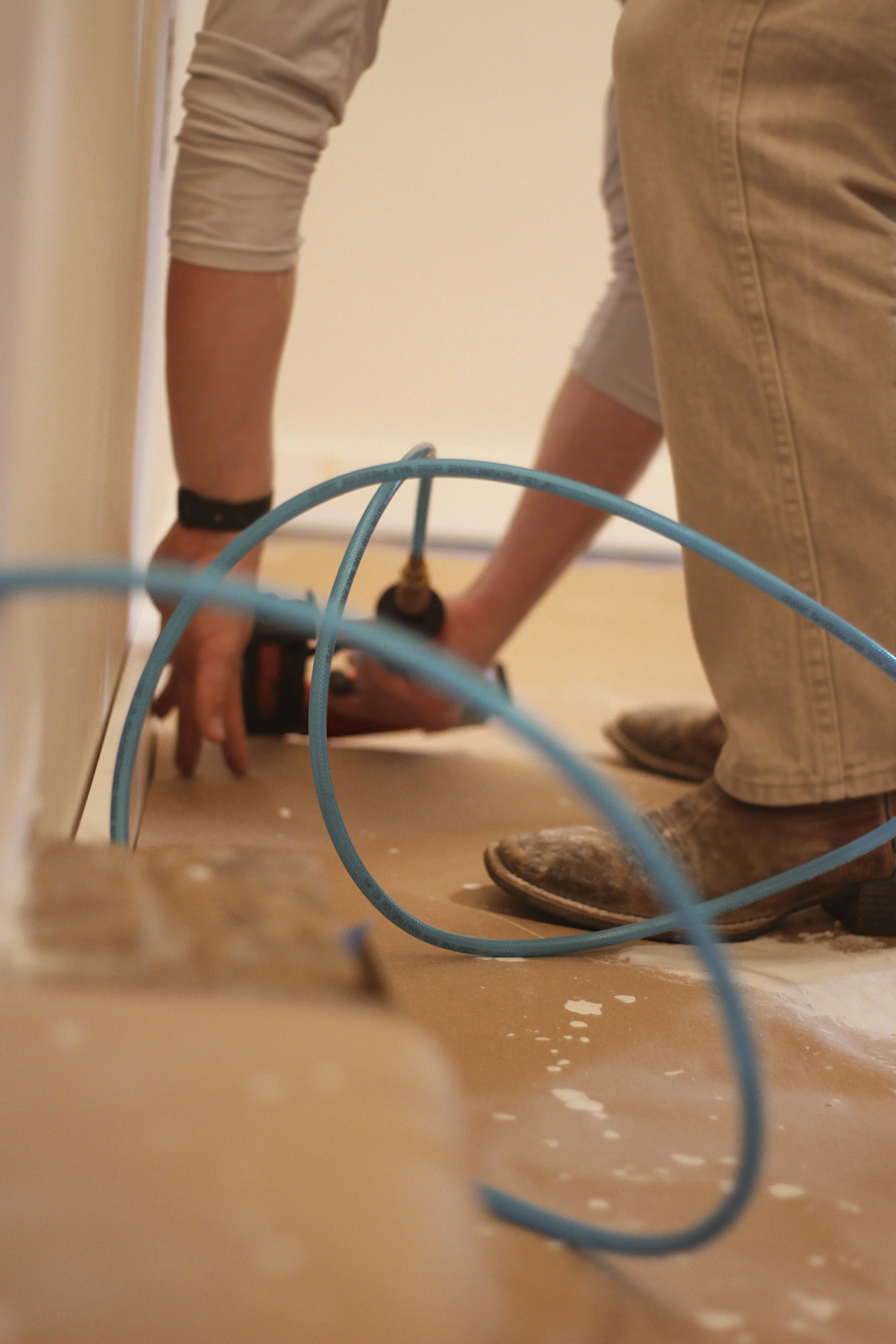 Person installing or working with air conditioning or ventilation system using a drill, on the floor near a wall.