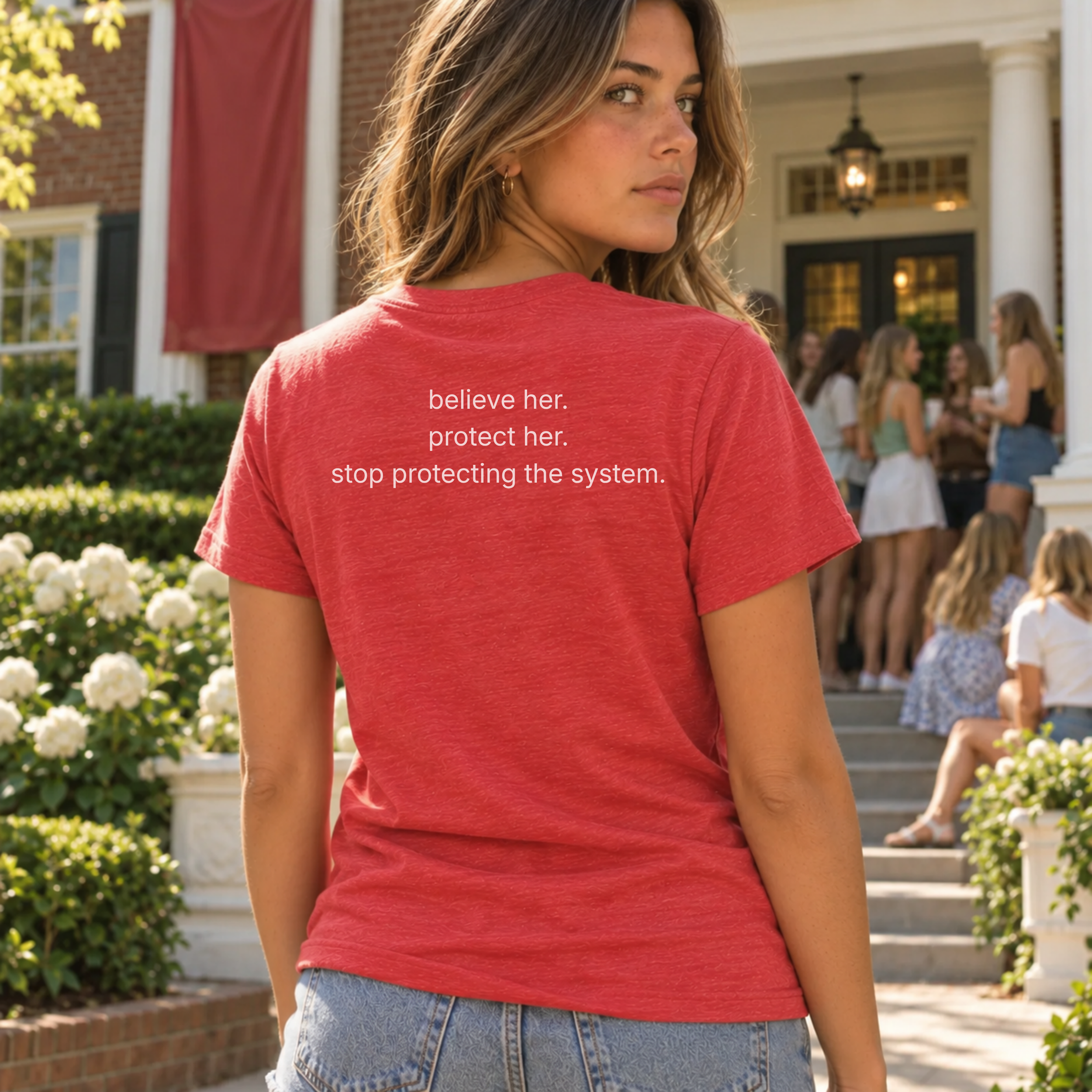 woman wearing the red jane doe t-shirt, back view: believe her. protect her. stop protecting the system.