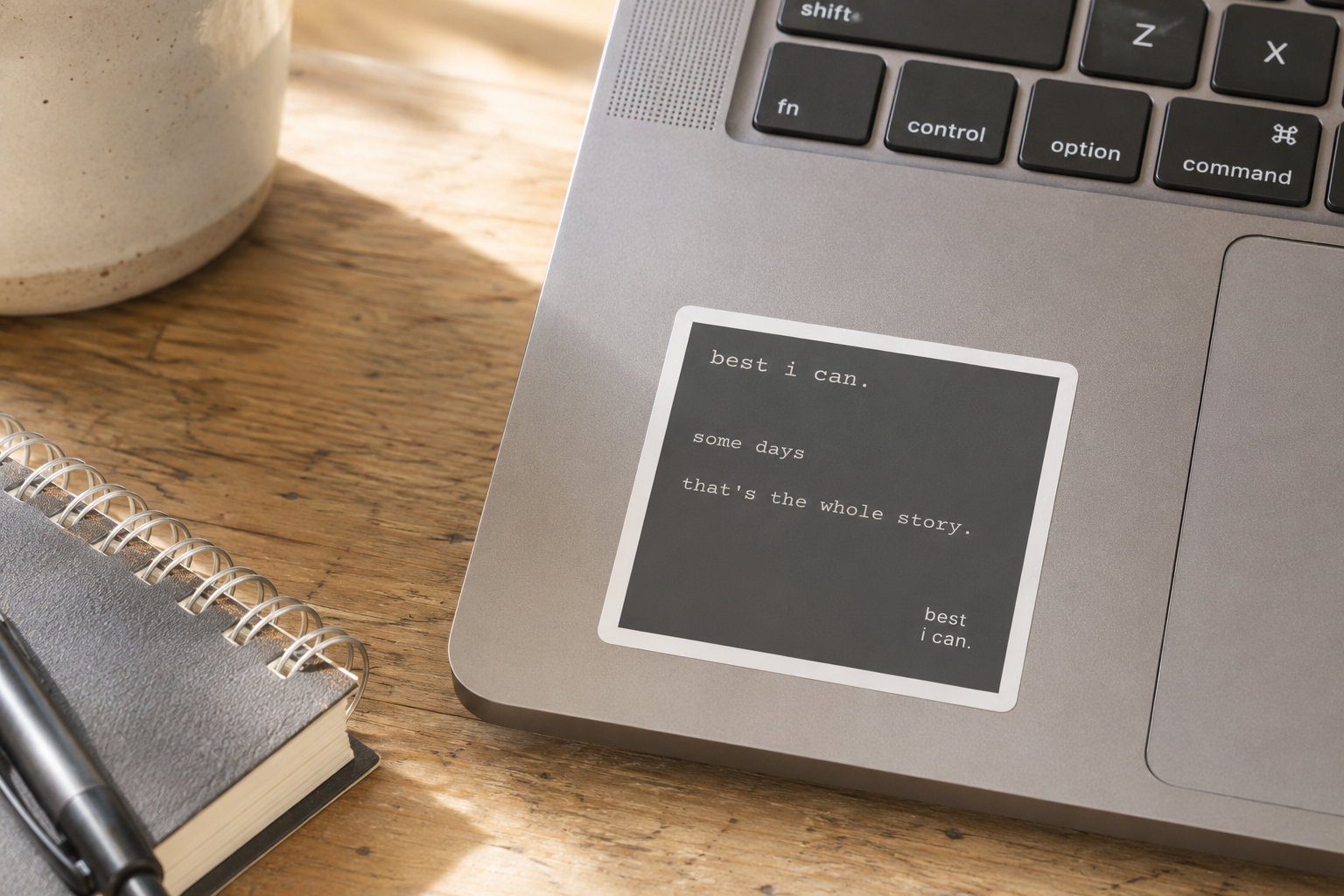 best i can sticker applied to a laptop beside a notebook and coffee mug on a wooden desk