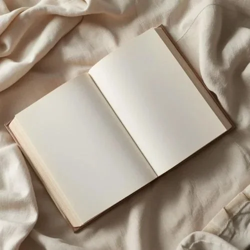 cover image for “this sucks.” — an open blank notebook on light fabric