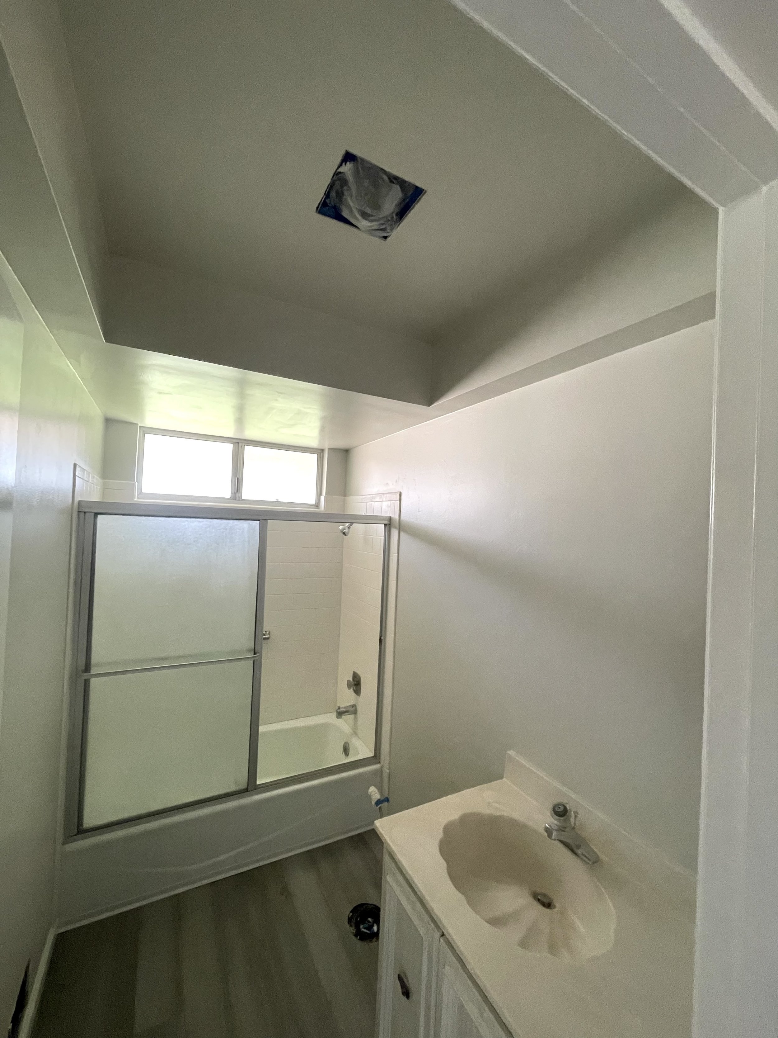 Bathroom with a fresh coat of light gray paint, a shower enclosure, a window, and a sink vanity.