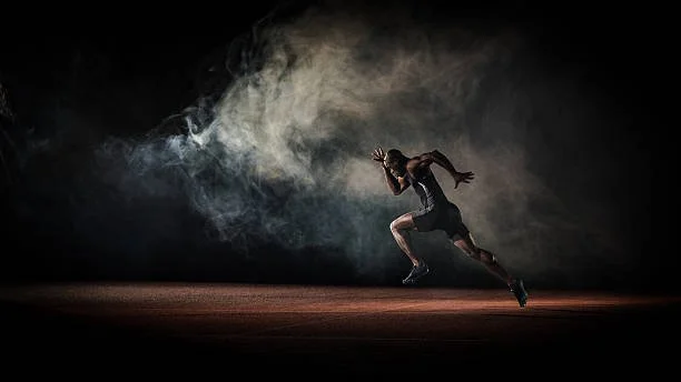 A person running on a dark stage with a trail of smoke behind them.