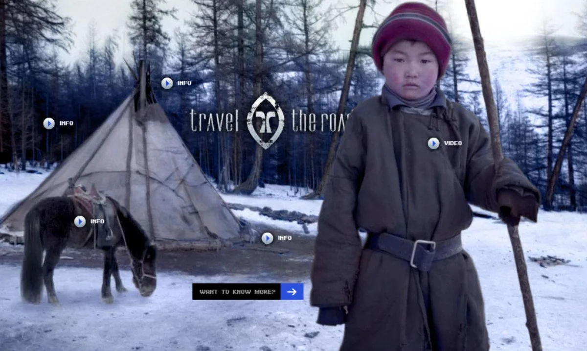A young child in winter clothing standing in front of a tent in a snowy forest, with a horse nearby and a logo in the background reading 'Travel the Road'.