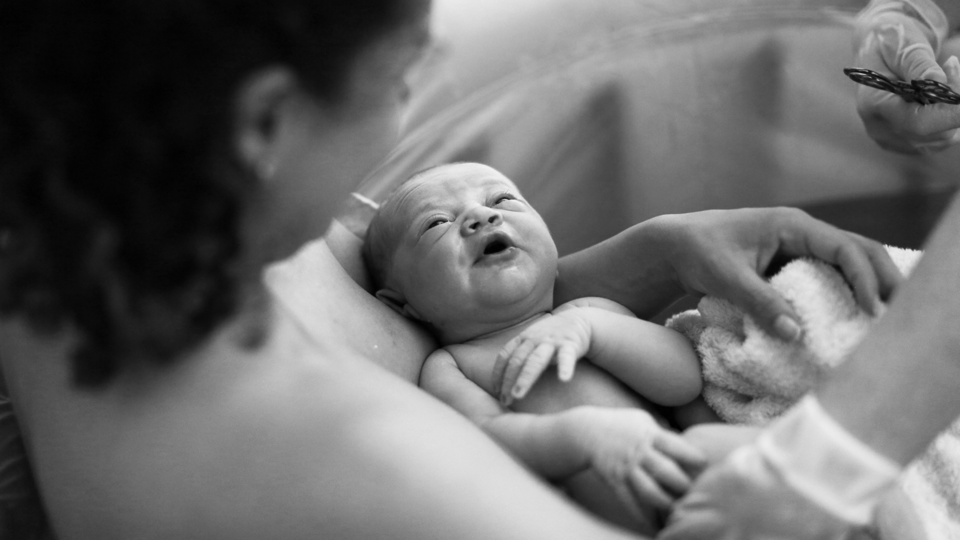 woman holding her newborn in birth tub