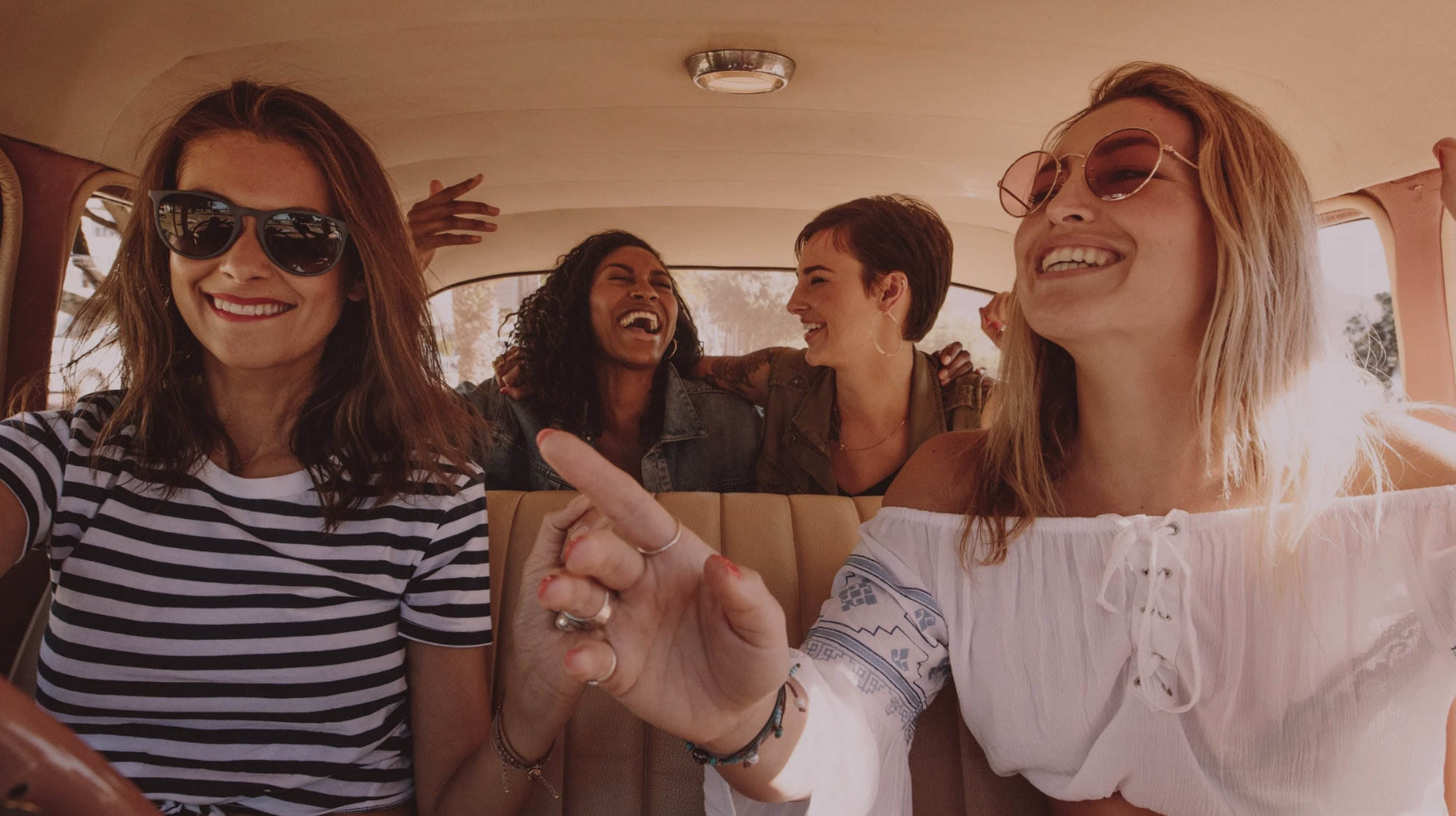 Four women in a van, laughing, signing and dancing.