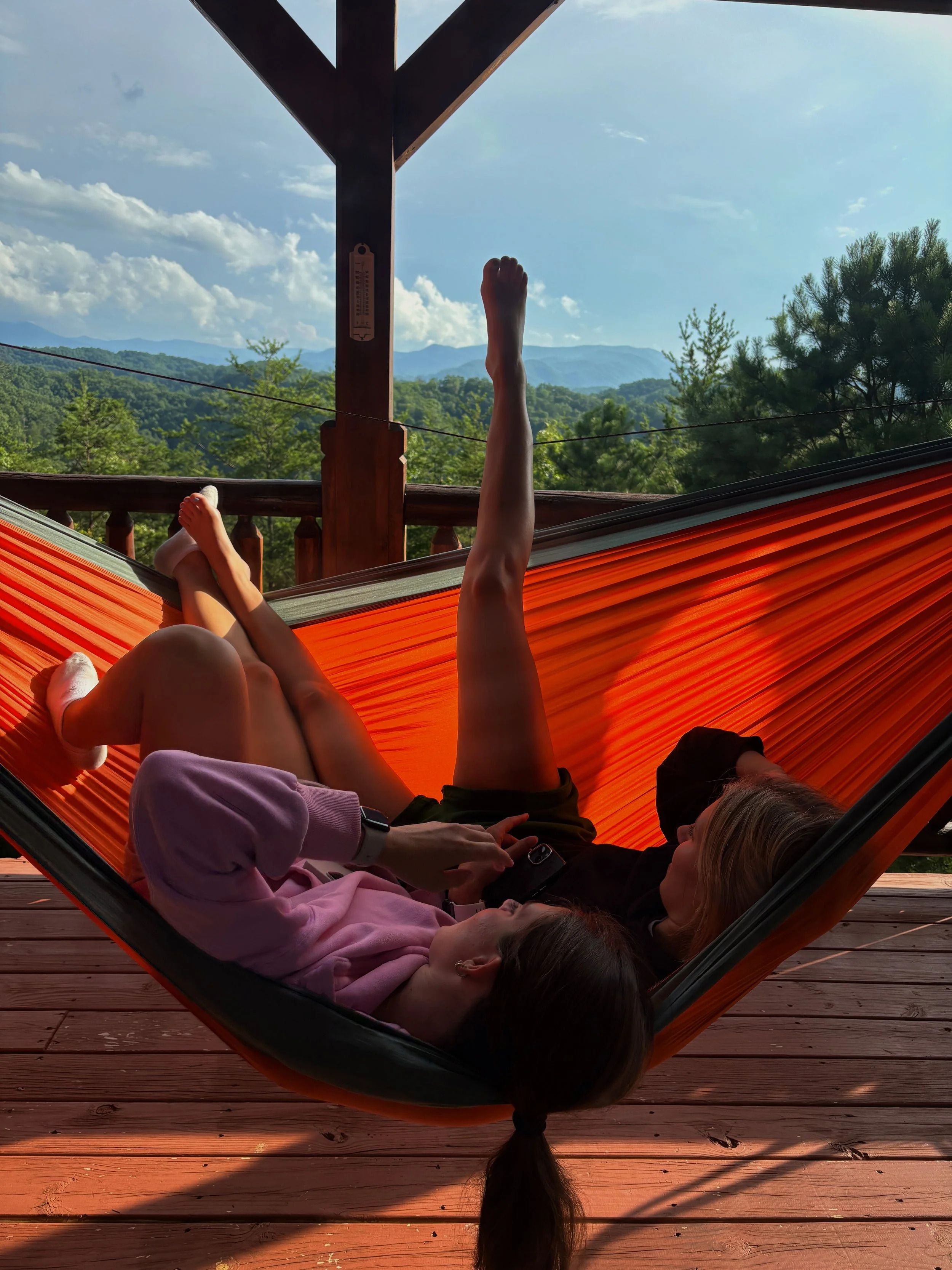 Two women laying on a hammock