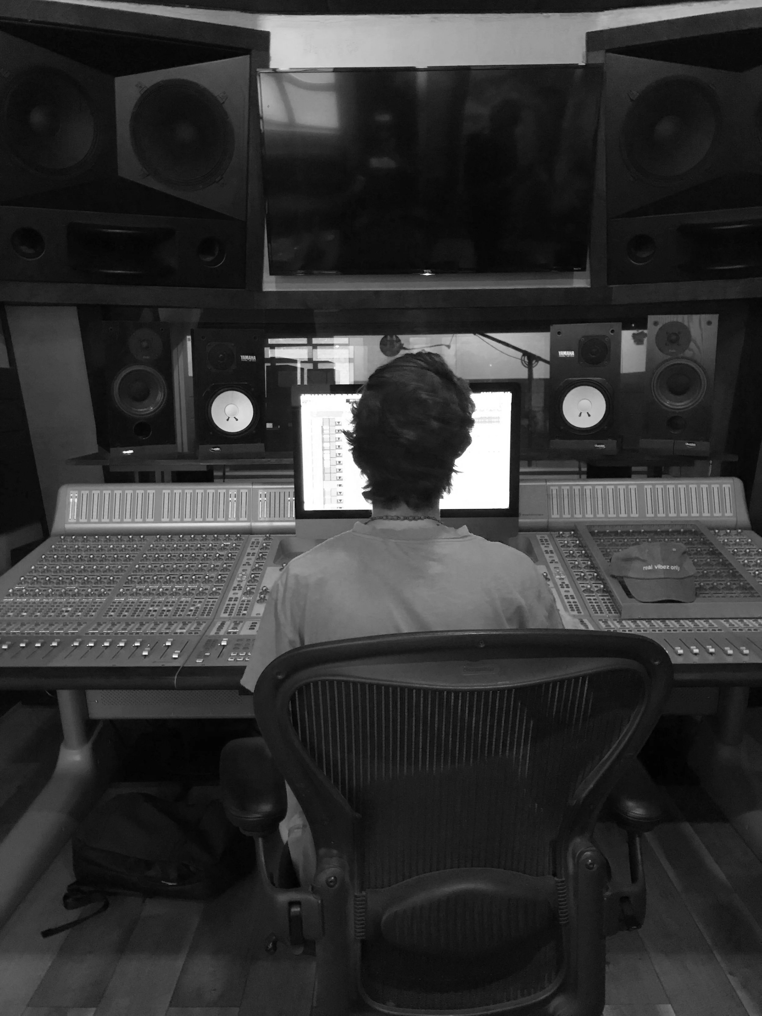 Person working at a music mixing console in a professional recording studio with multiple speakers and monitors.