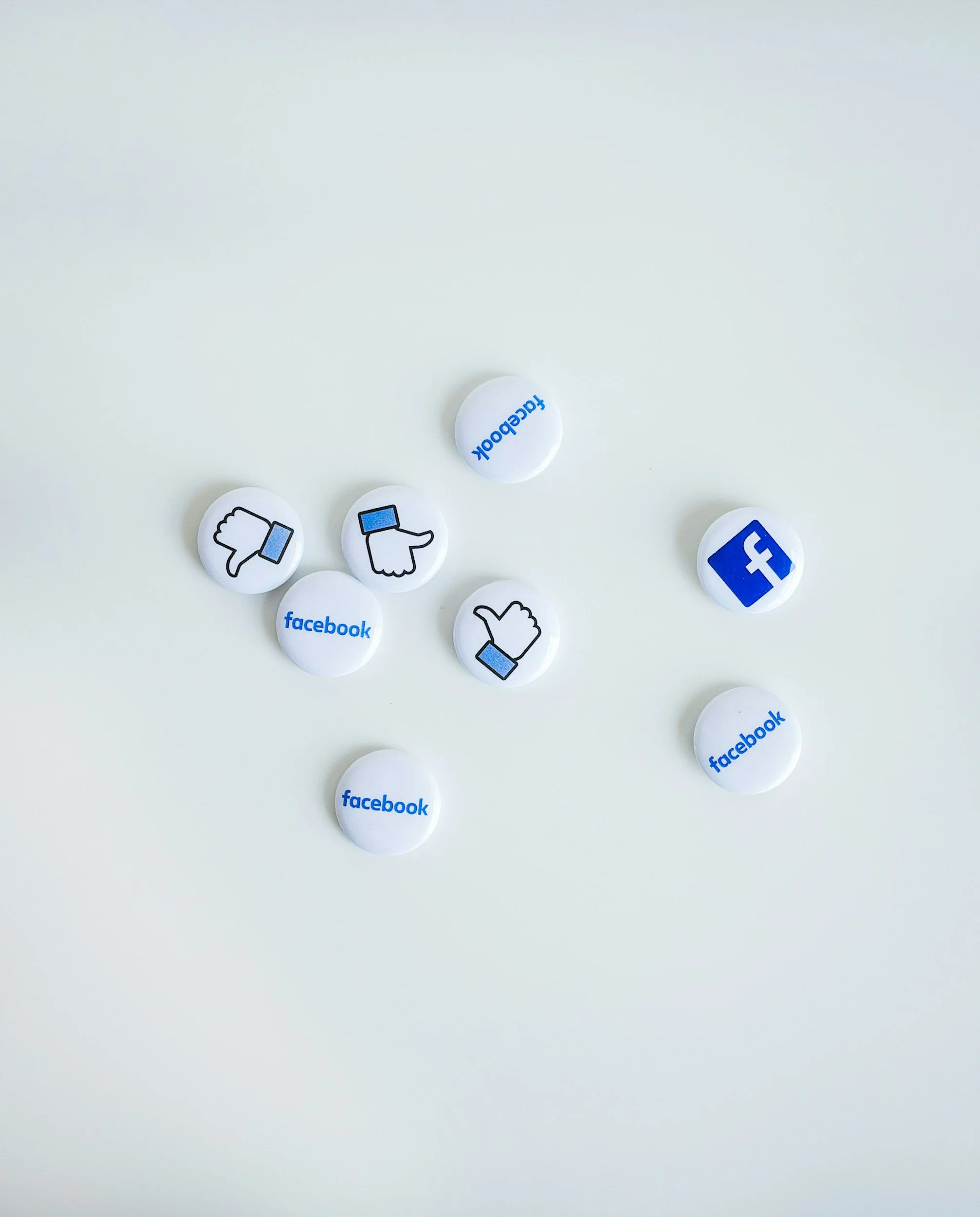 Scattered Facebook-themed buttons with thumbs up, thumbs down, and Facebook logo on a light background.