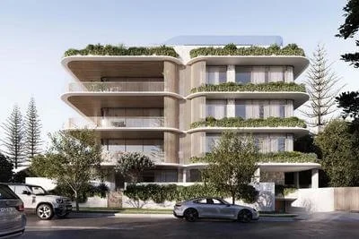 Modern multi-story building with curved balconies and greenery, parked cars in front, trees lining the street.