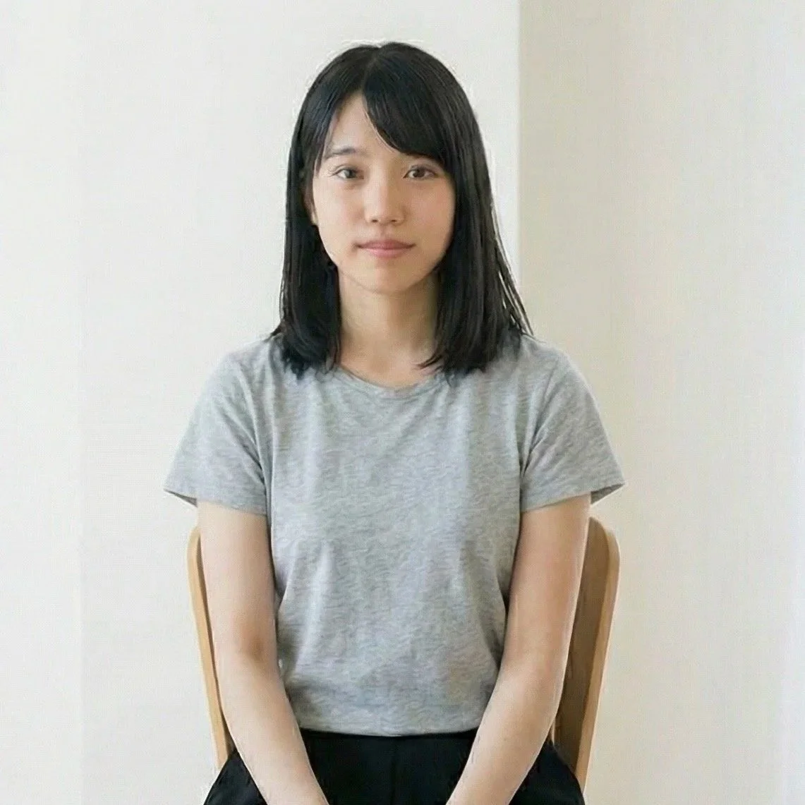 灰色のTシャツを着た若い女性が椅子に座っている写真