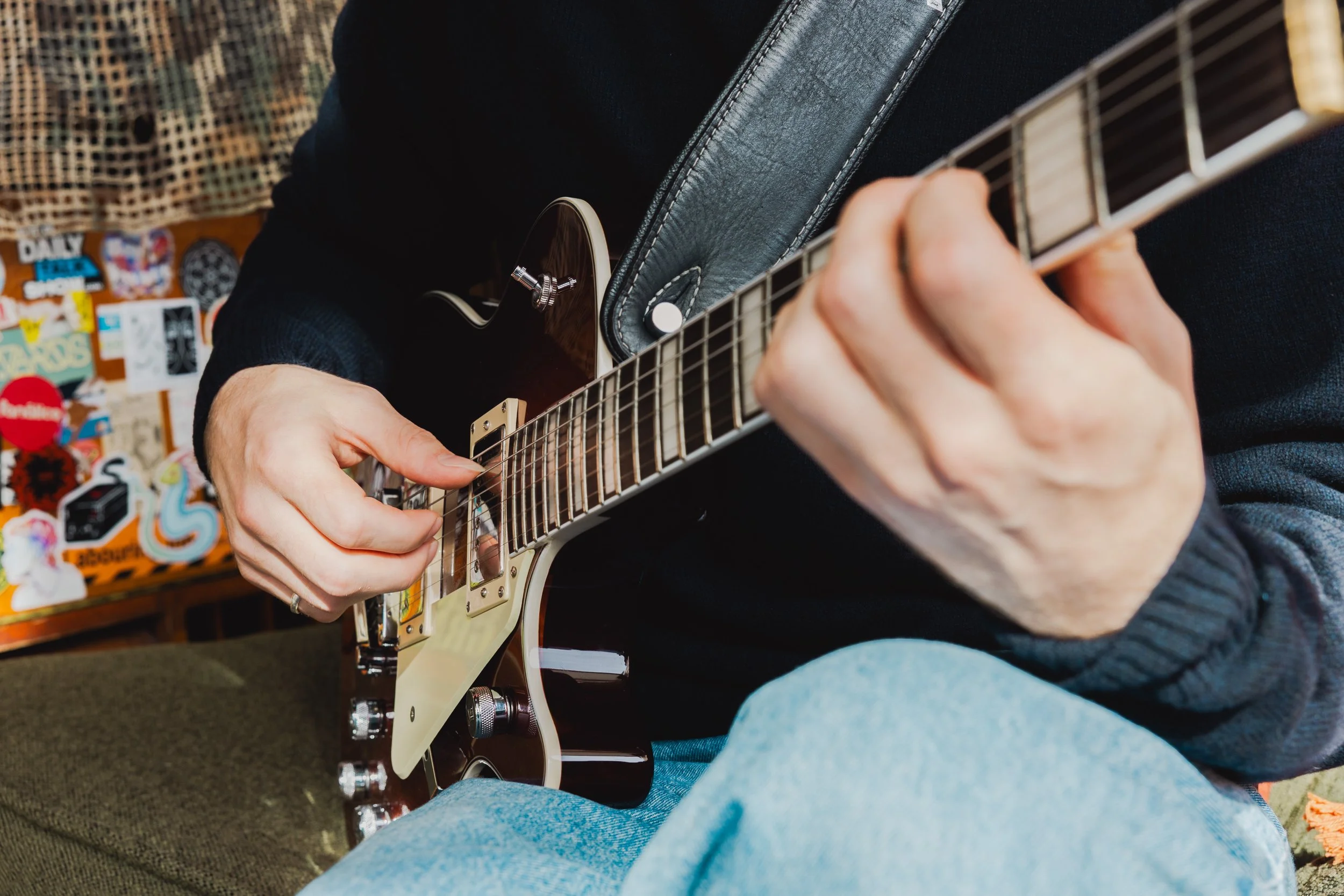 Person playing an electric guitar Melbourne, focusing on their hands and the guitar neck.