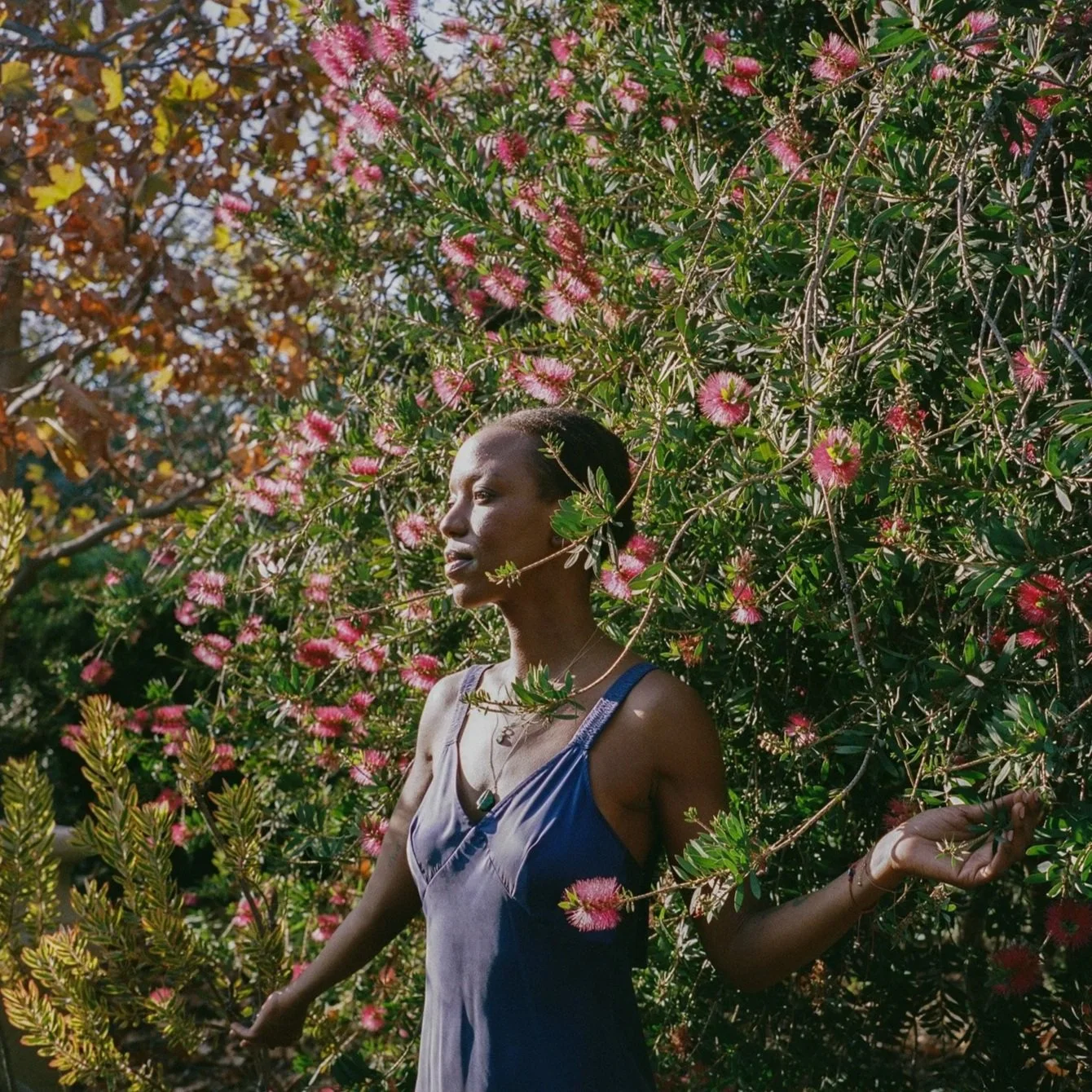 Wandie Kabule, a Certified Level III Reiki Master, standing in a serene nature setting.