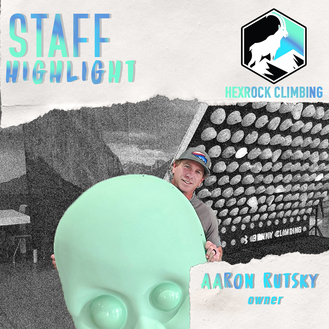 A smiling man in a black t-shirt and cap holding a blue climbing crash pad indoors, with a window in the background. Text on the image highlights staff and owner Aaron Rutsky at Hexrock Climbing.