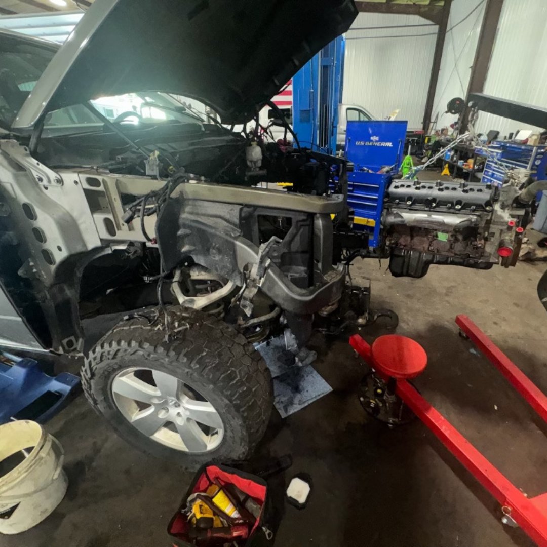 Partially disassembled vehicle in a garage, with tools and equipment around it.