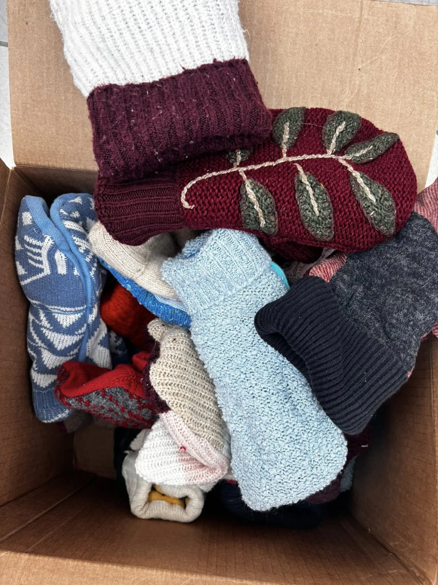 A box filled with various folded socks of different colors and patterns.