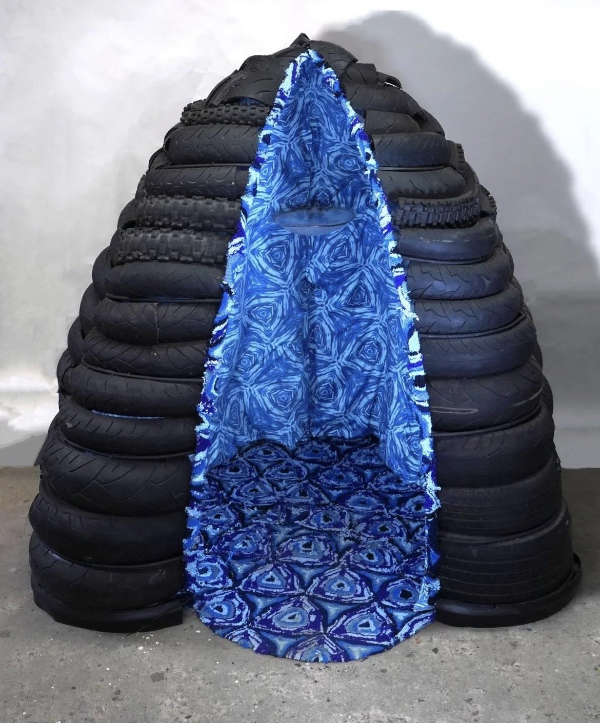 Dream Womb, 74" x 64" x 60", repurposed tires, steel, printed fabric, tufted rug, plexiglass, fishing bobbers, paint, poetry, 2023