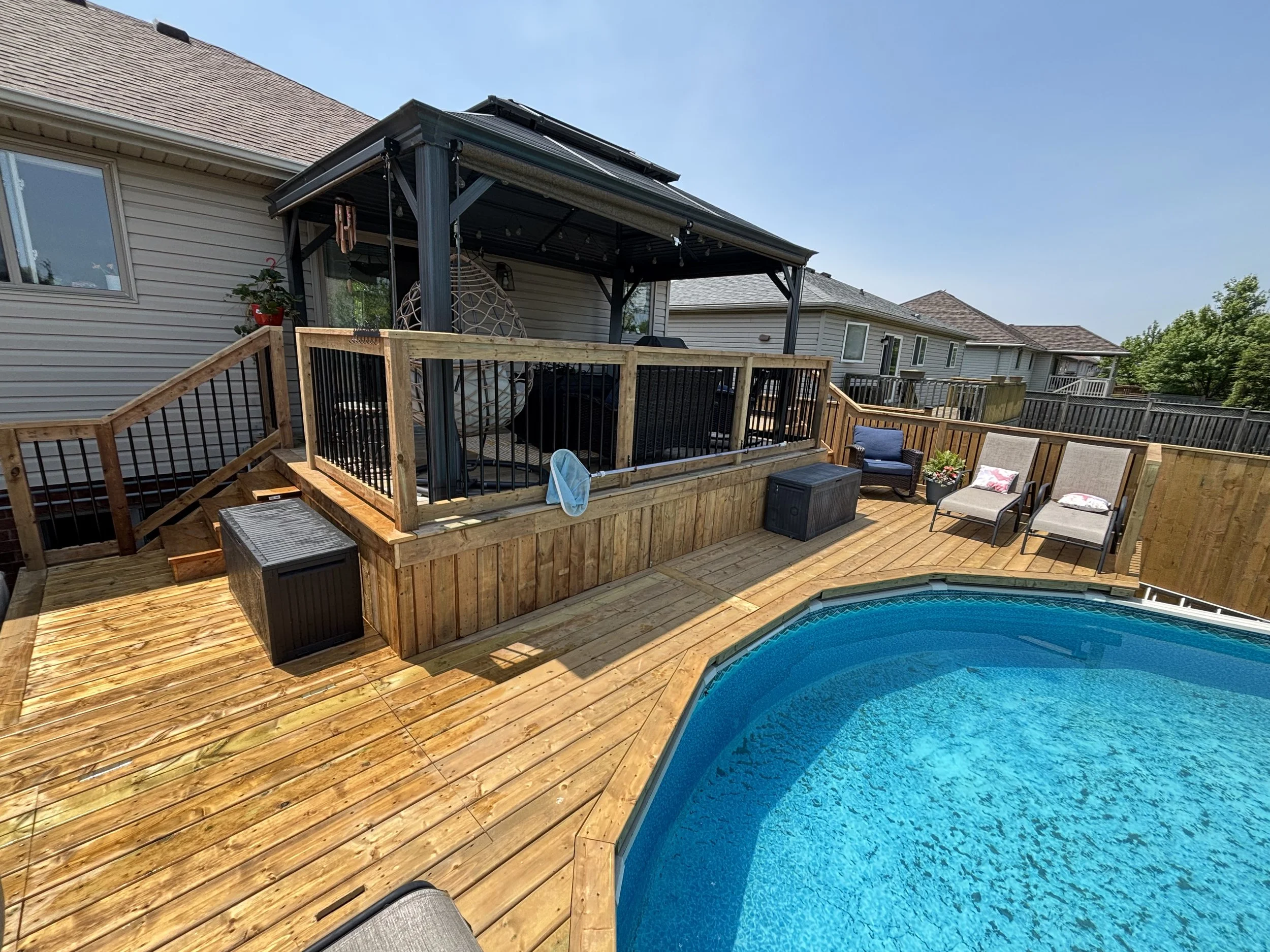 Backyard with swimming pool, wooden deck, outdoor furniture, and a covered patio area.