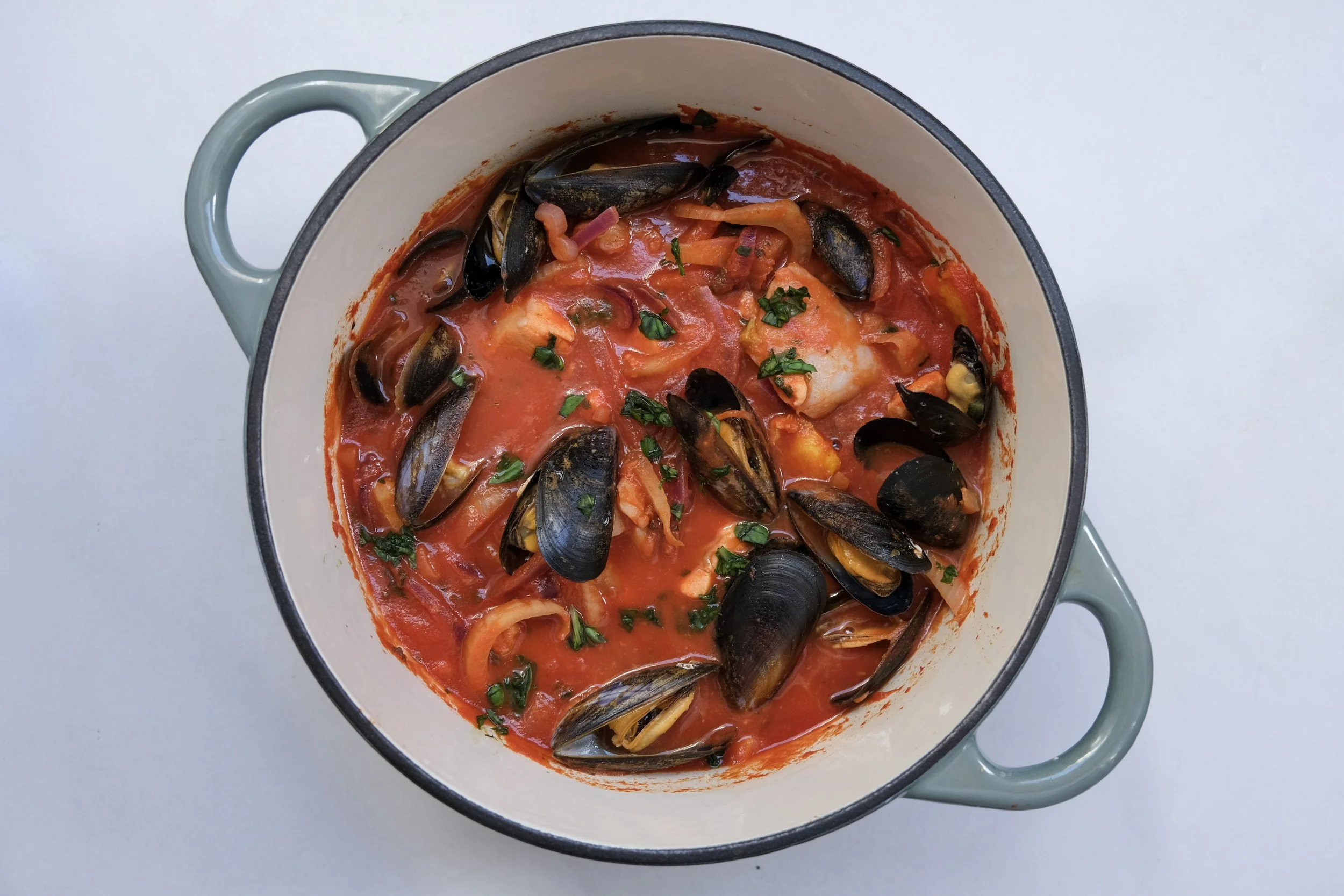 One-pot salmon, mussel, and fennel seafood stew in a ceramic pot.