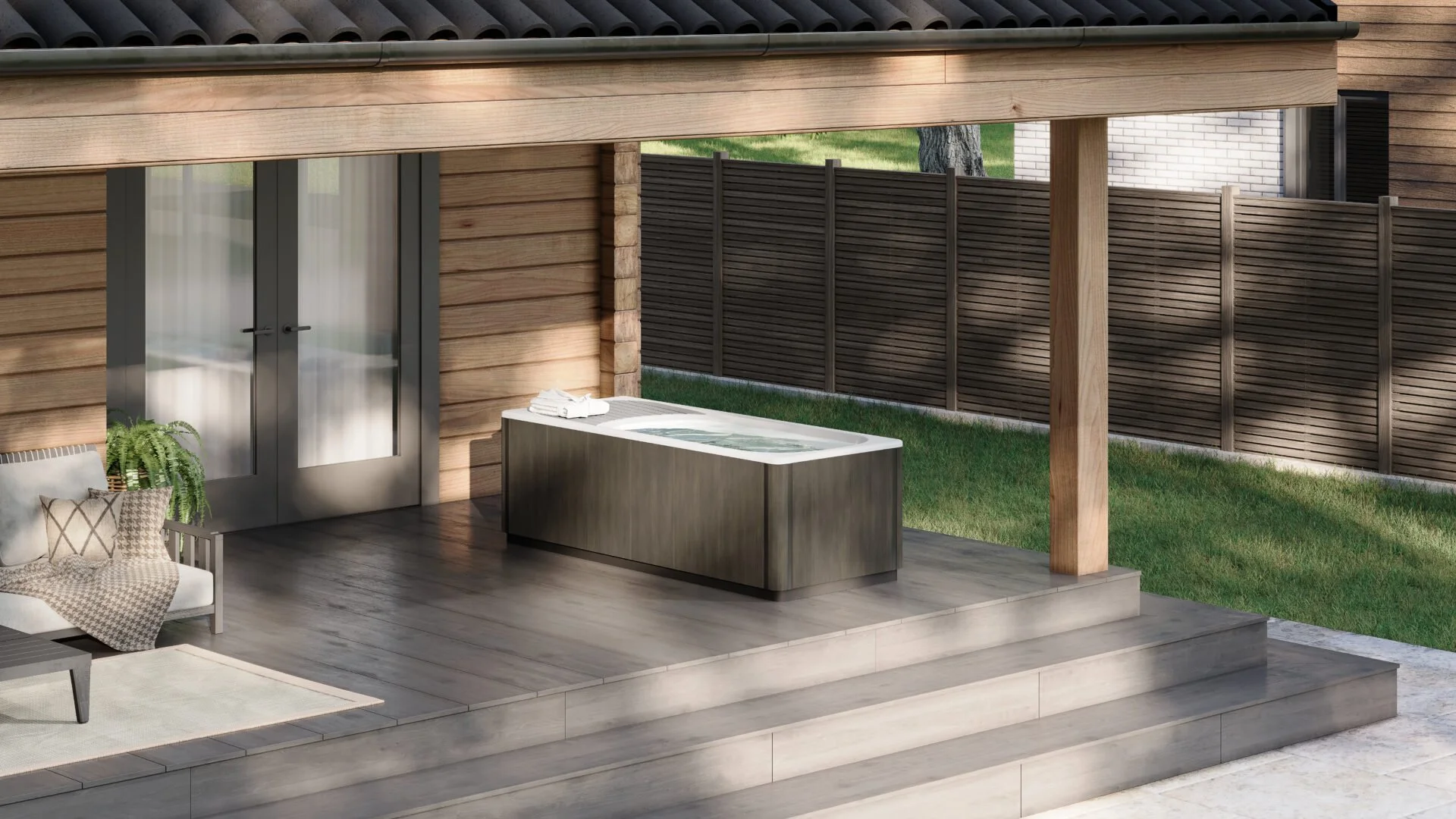 Backyard patio area with a hot tub, sofa, and decorative cushions, enclosed by a wooden fence.