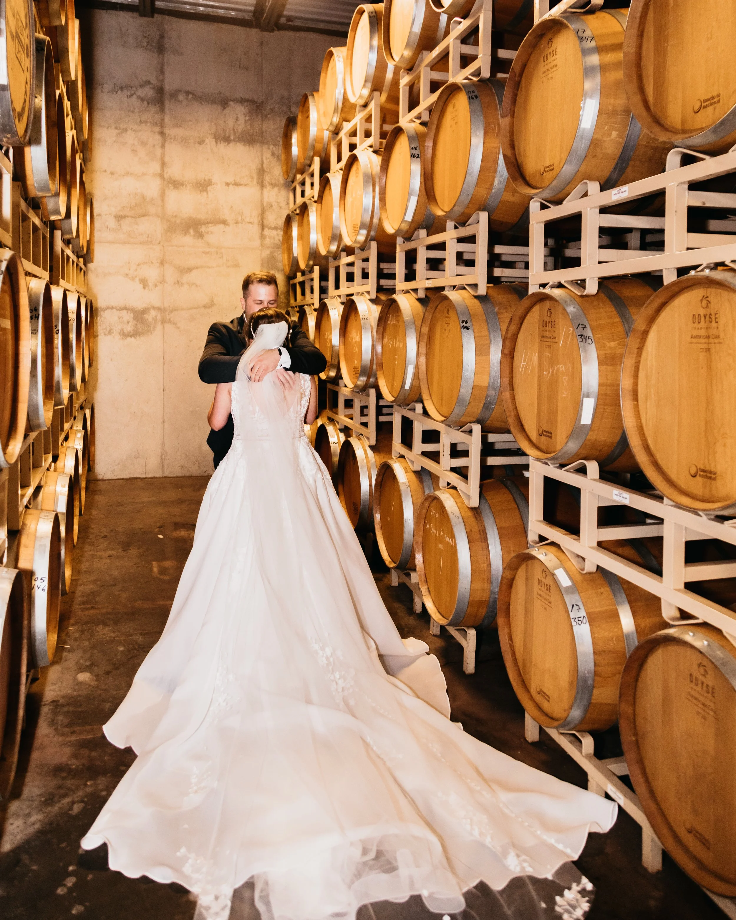 A newlywed couple dancing in a wine cellar surrounded by stacked wine barrels at Balistreri Vineyards Denver Colorado