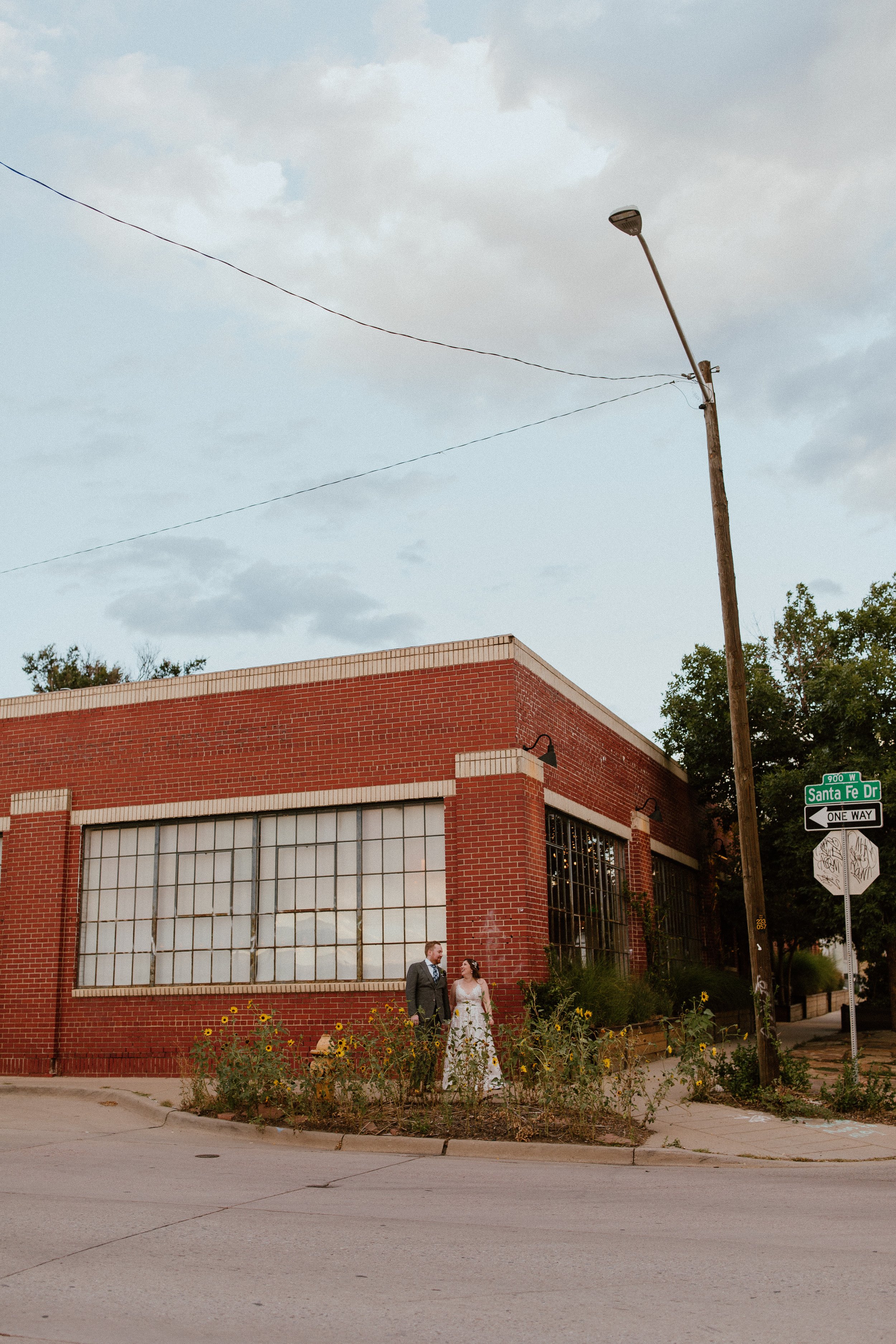 A bride and groom standing together on a sidewalk in front of Moss Denver Colorado Wedding Planner Denver Colorado Santa Fe Drive. Denver professional wedding coordinator planner