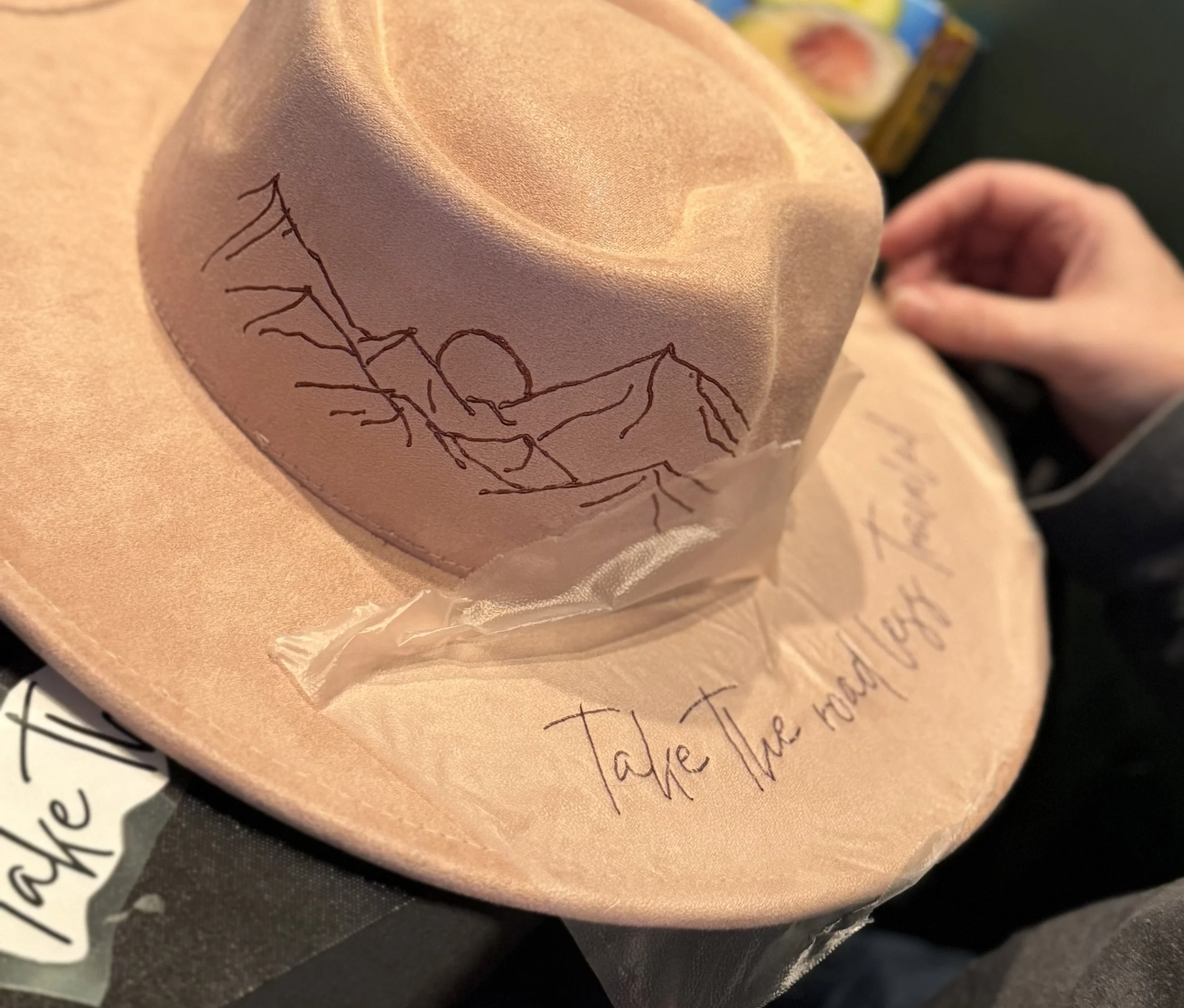 A peach-colored balloon with a black line drawing of a person holding hands with a child, and handwritten text underneath, partially visible, that says "Take me".