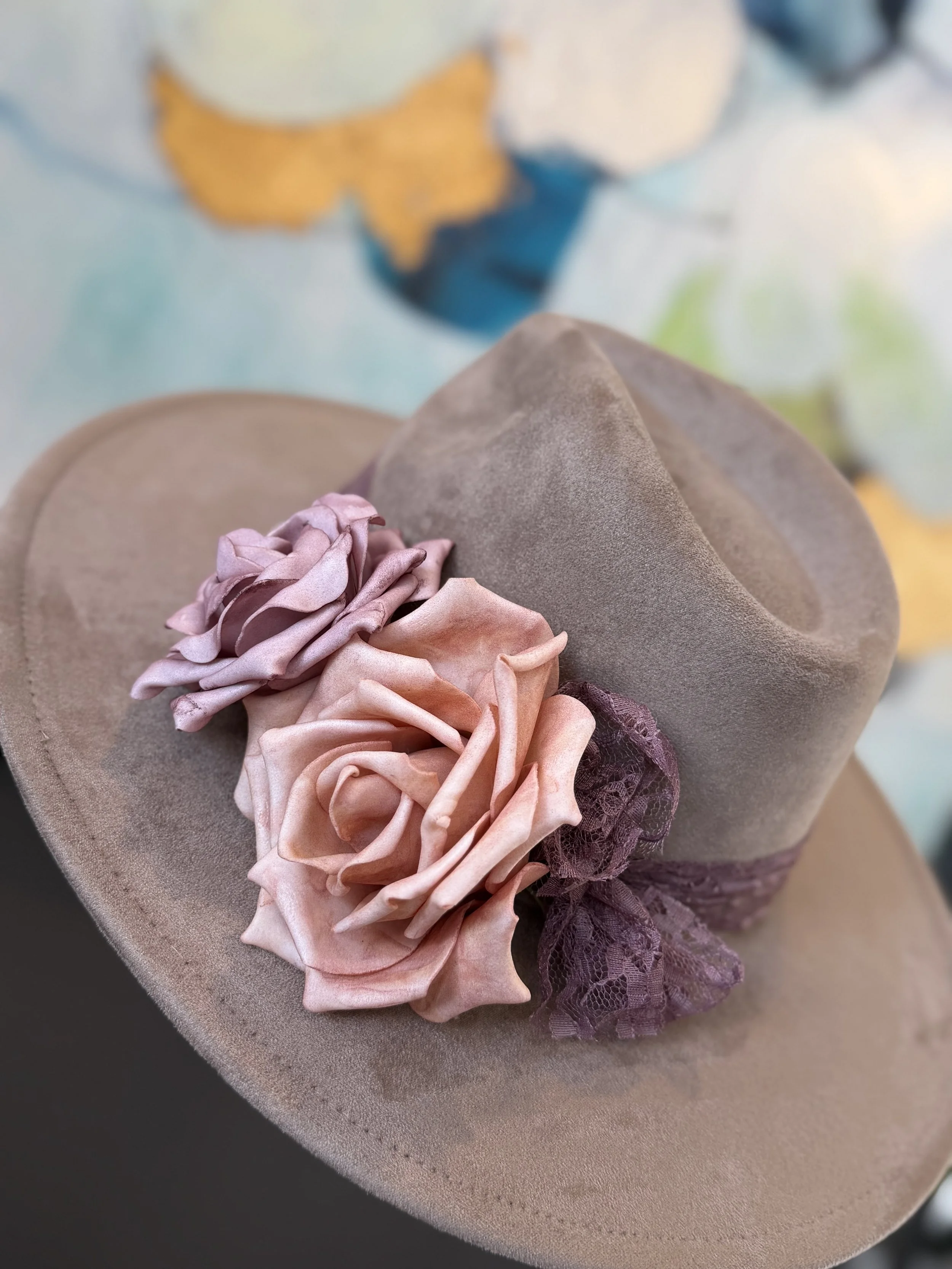 Close-up of a decorative arrangement on a pink table, featuring pink and beige fabric flowers and lace ribbons.