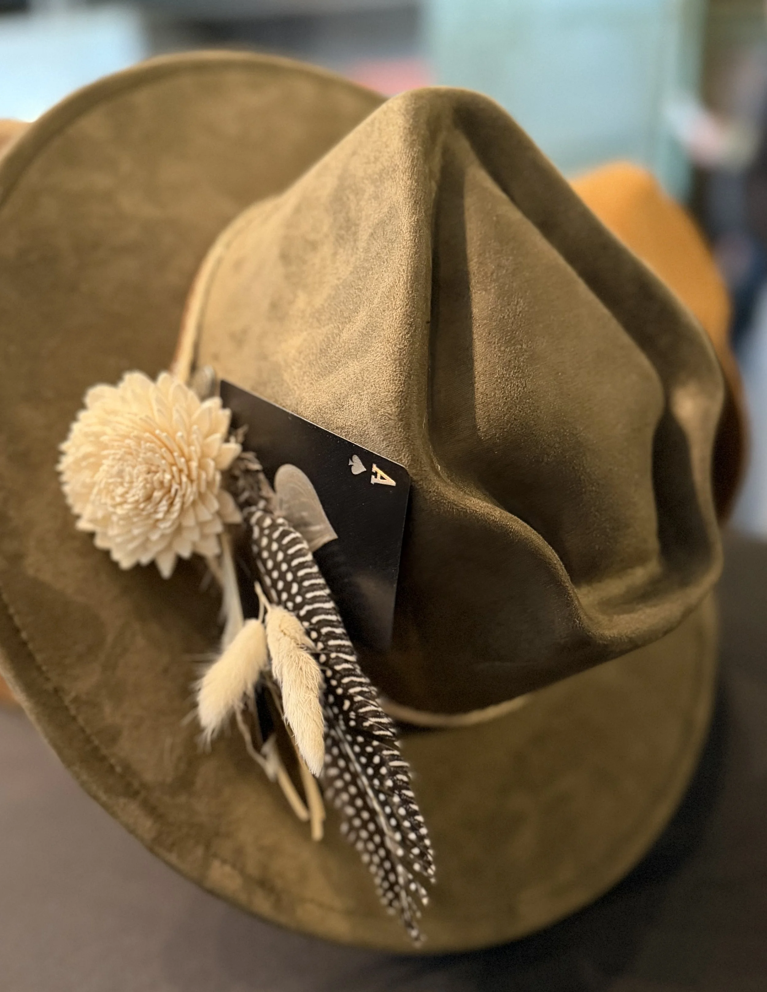Close-up of a cardboard box with a textured, soft fabric interior, decorated with a beige flower and black-and-white striped feathers.